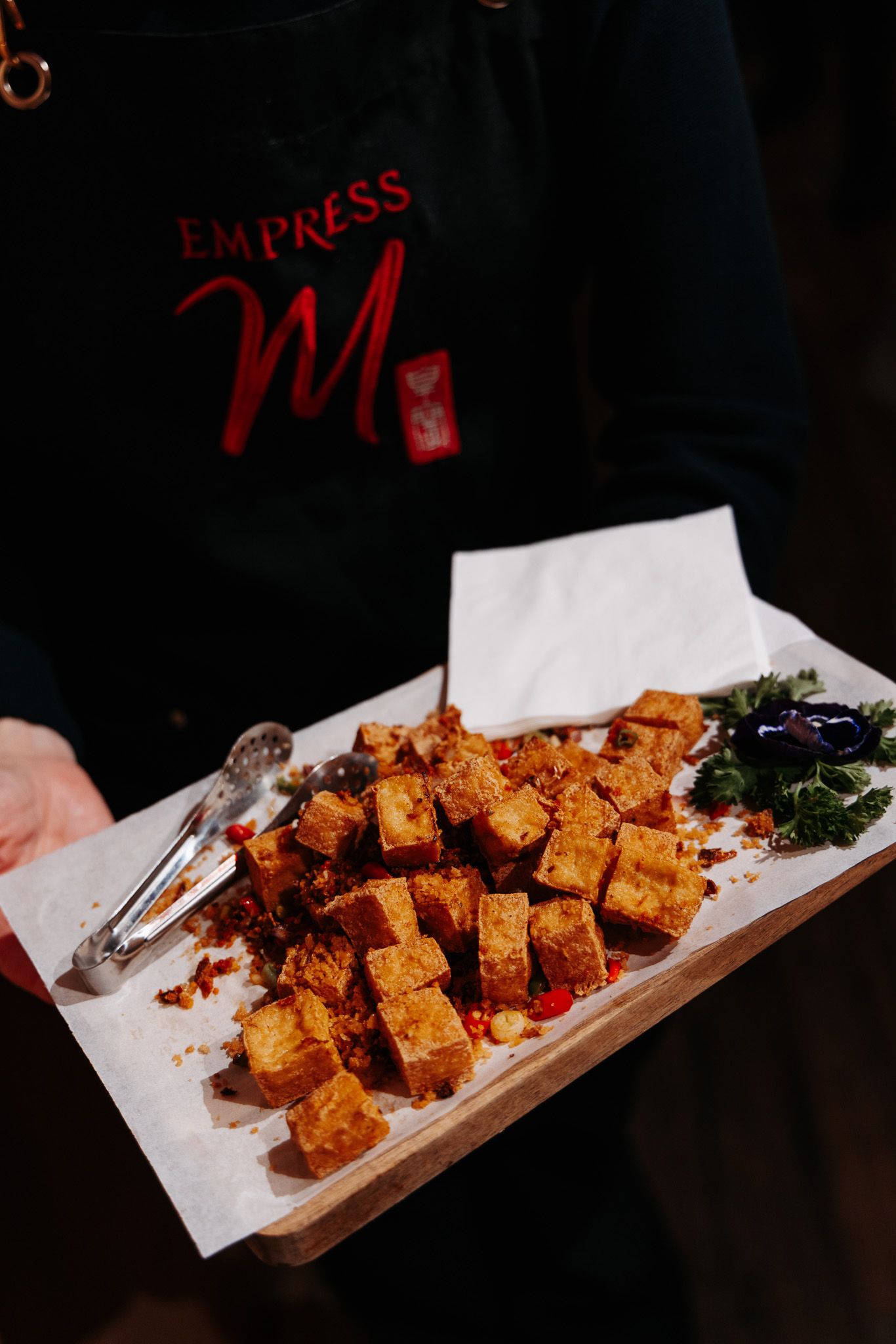 Grilled or fried tofu cubes arranged on a wooden serving board with garnish.