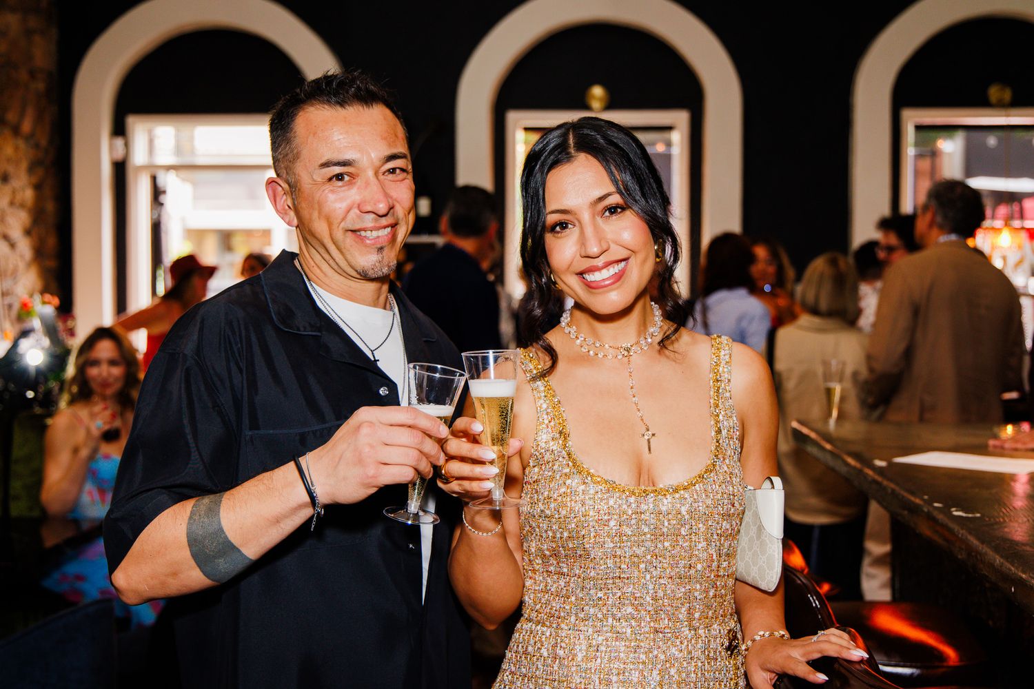 Man and woman smiling and toasting with champagne glasses at an elegant party event.