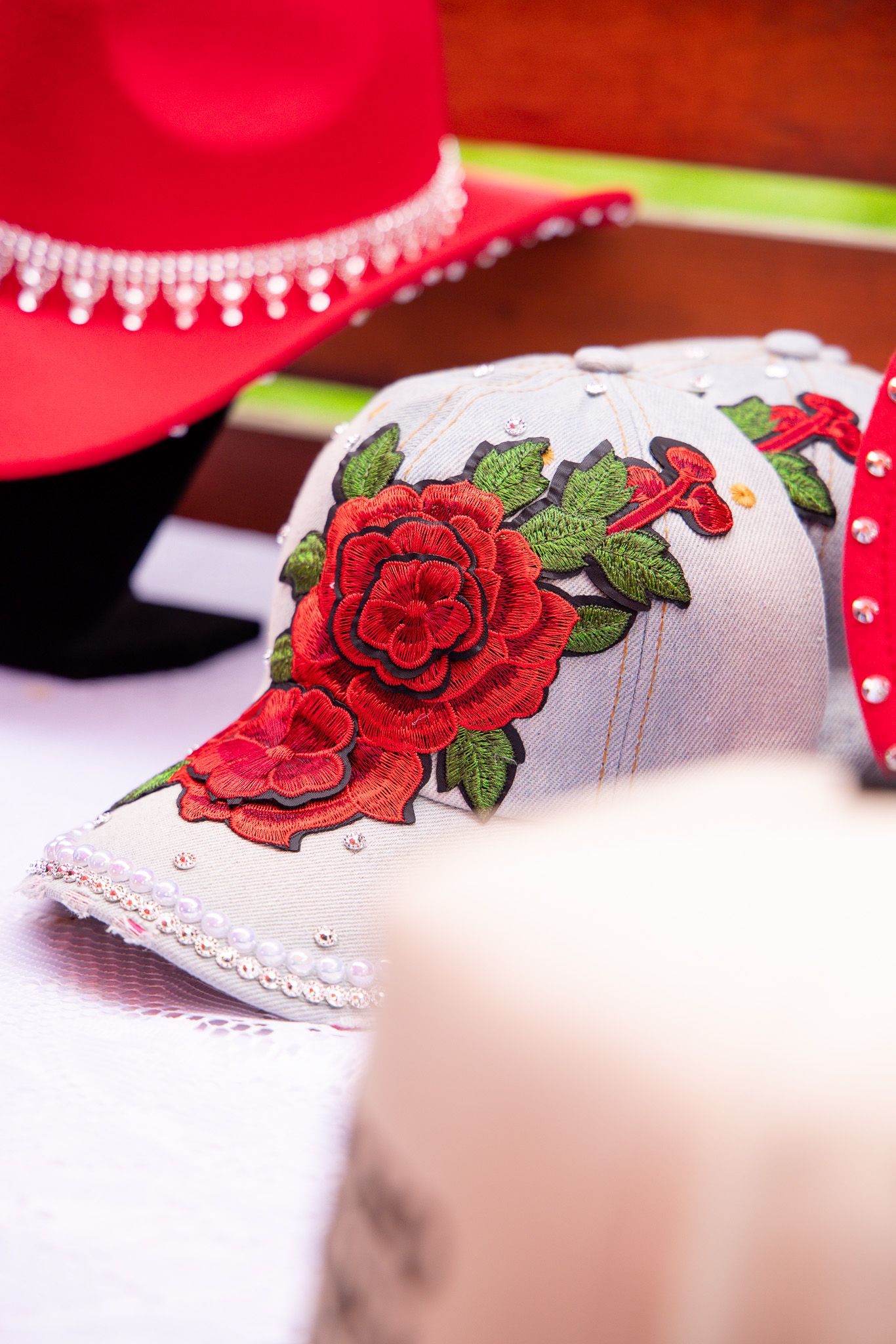 Close-up of embroidered red roses on white fabric with lace trim.