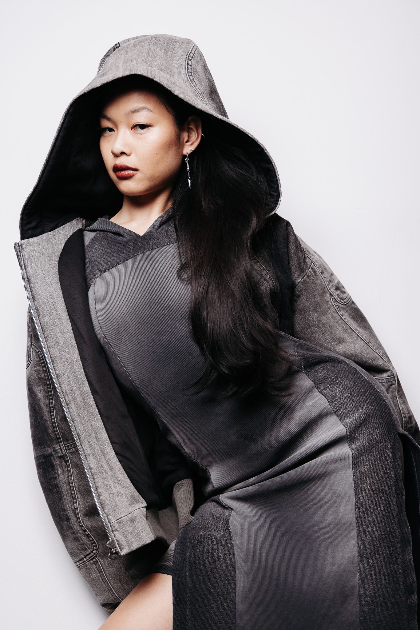 Fashion portrait featuring a black dress and oversized gray coat in dramatic monochromatic studio lighting.