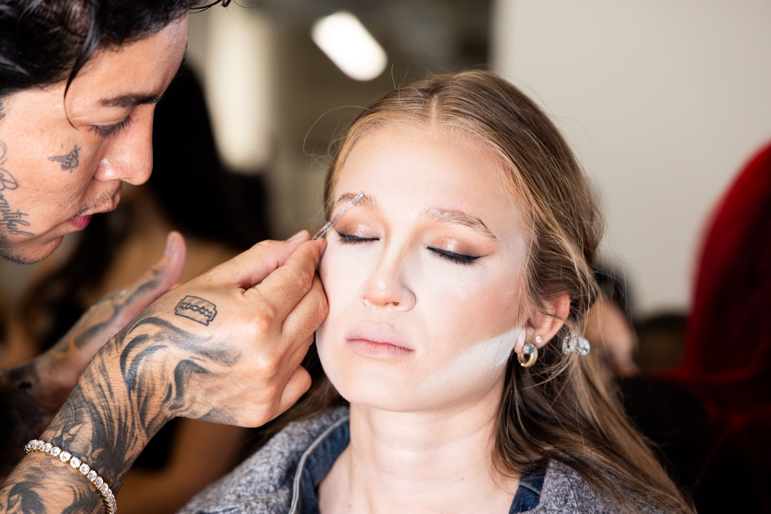 Professional makeup artist applying eyeshadow and beauty products during a glamorous beauty session.