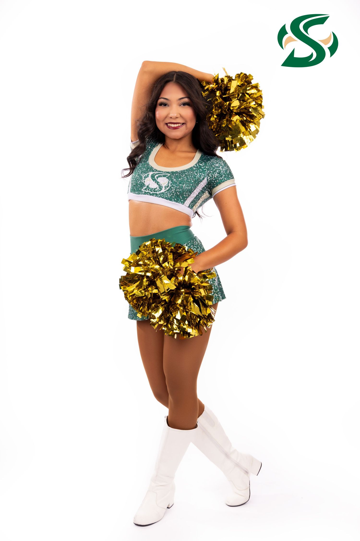 Cheerleader in green and white uniform holding gold pom poms poses with high energy.