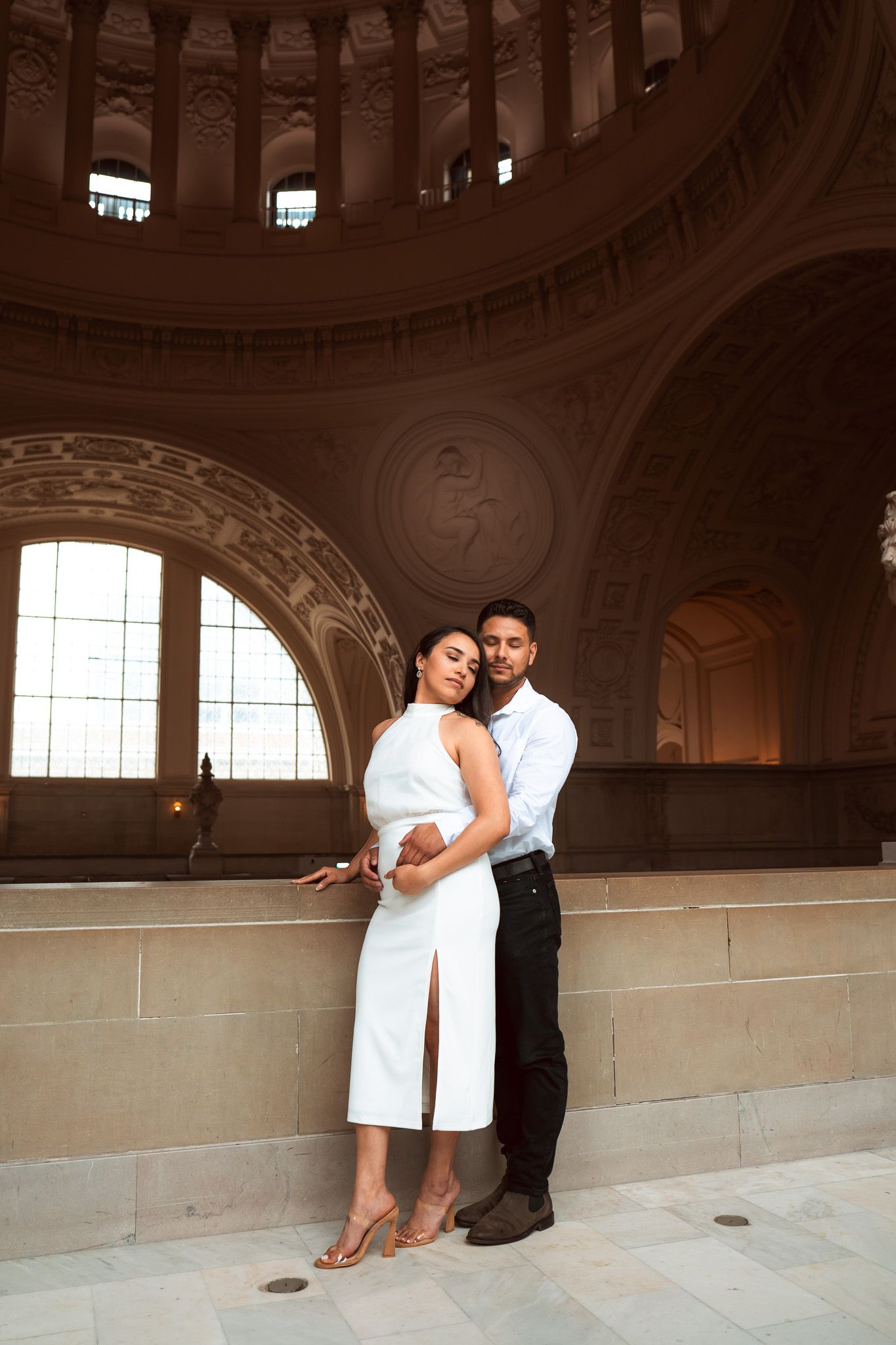 A romantic engagement photo series showing a couple in an elegant architectural setting with arched windows and ornate details.