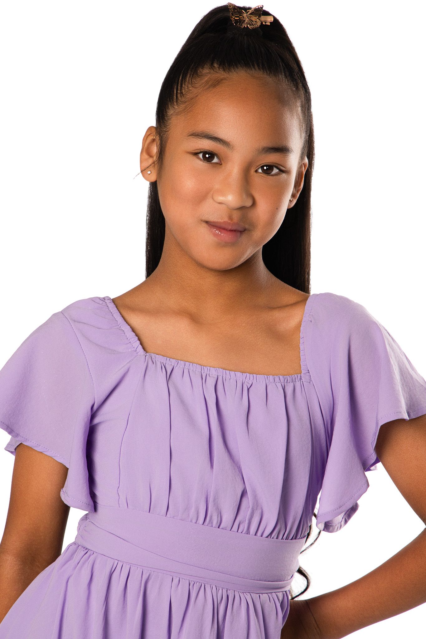 Studio portrait of a young person in a lavender flutter sleeve dress against a white background.