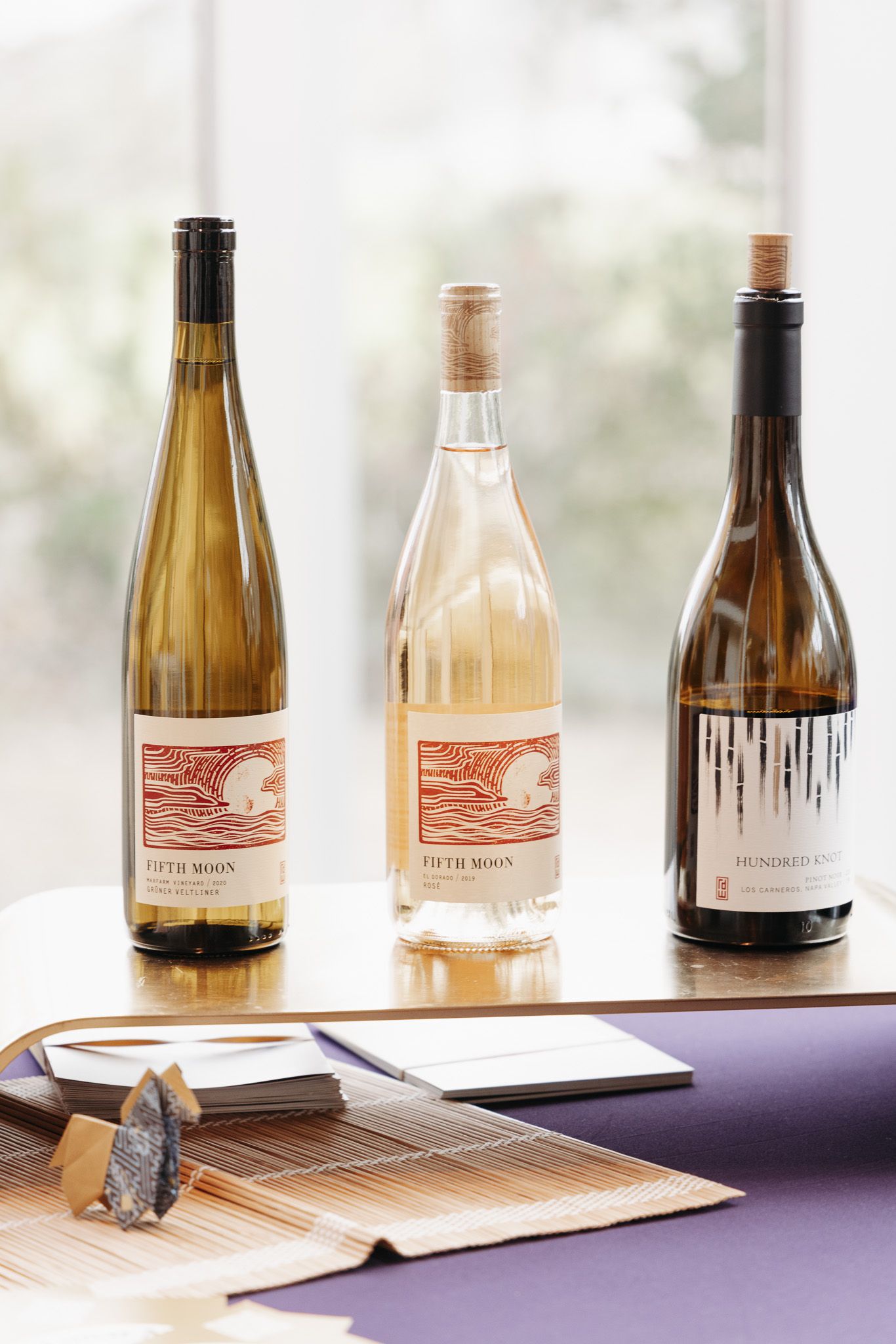 Three wine bottles displayed on a table with a serving utensil.