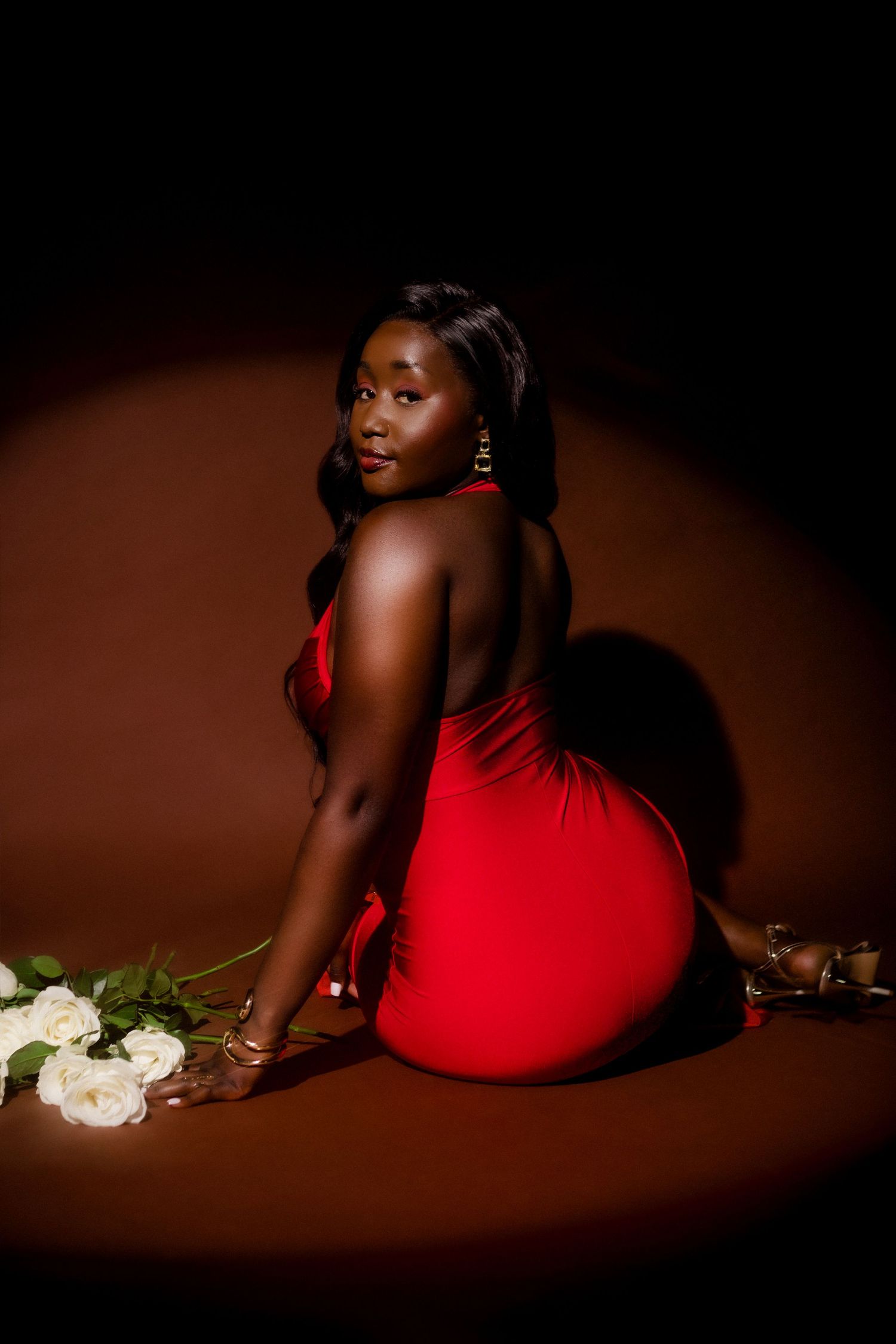 A stunning artistic portrait series featuring poses in red against a dark background with white roses as props.
