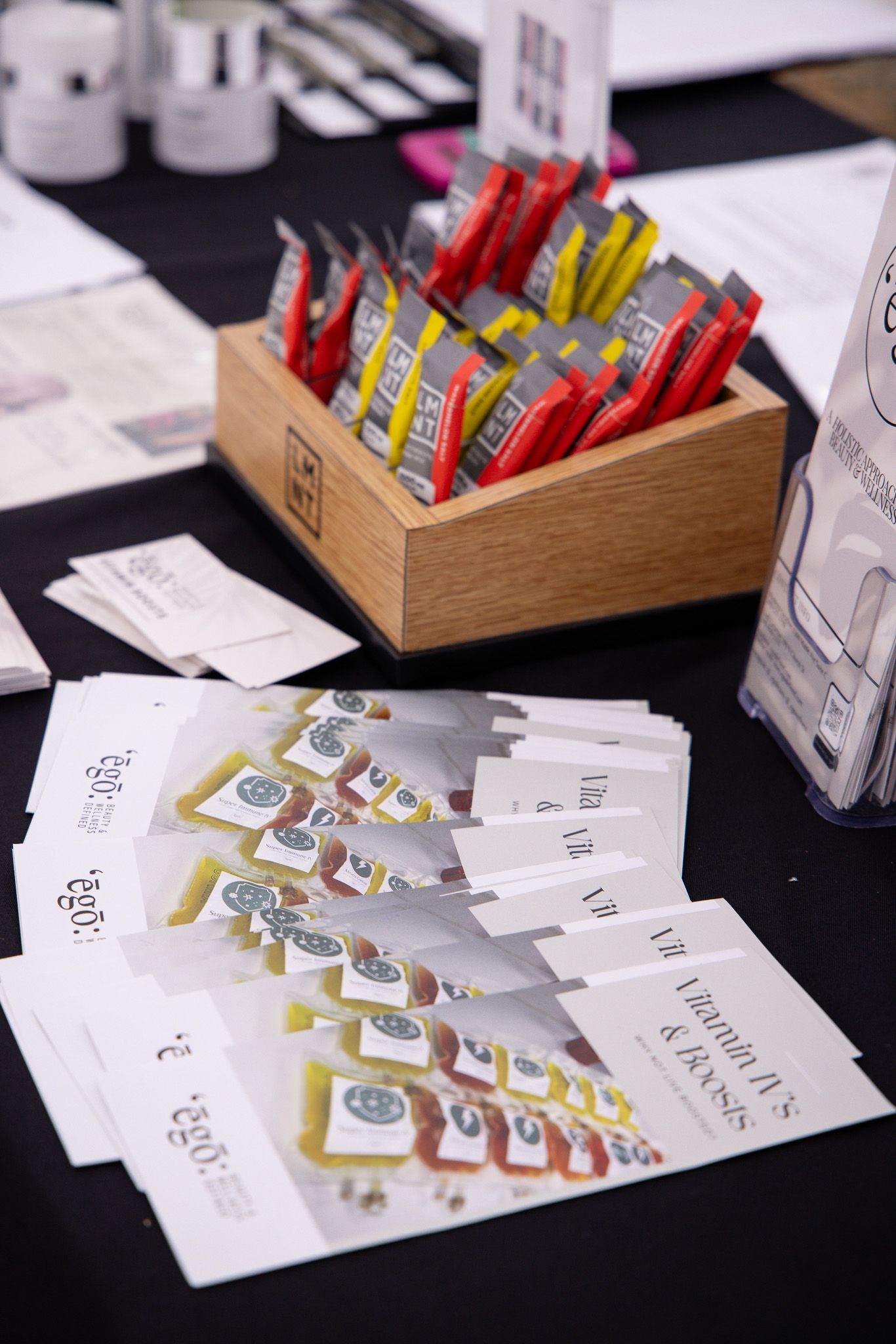 Marketing materials and promotional cards displayed on a black surface with a wooden box containing colorful items.
