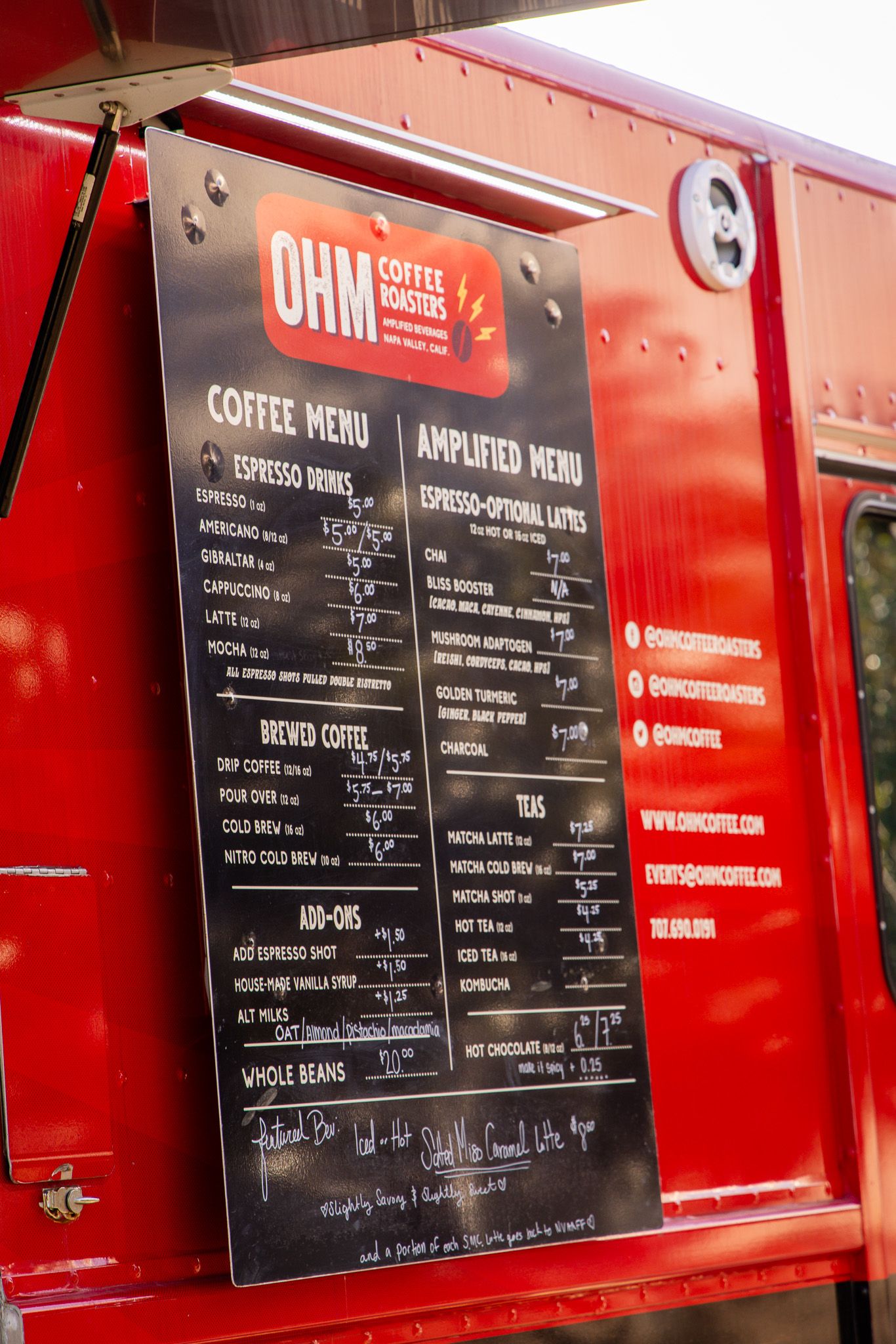 Red coffee shop menu board displaying drink options and prices.