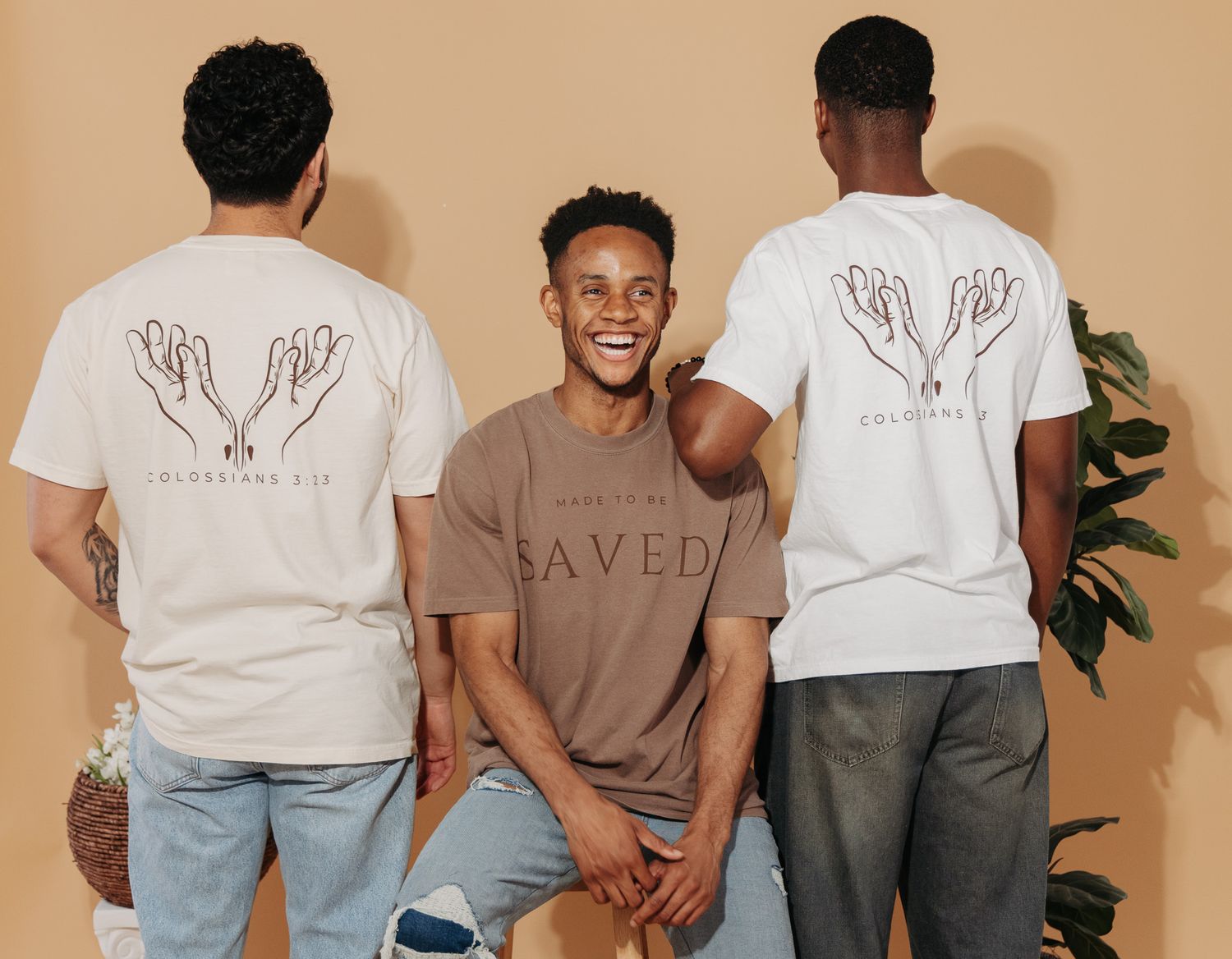 Models wearing brown and white t-shirts stand against a beige wall showing casual clothing collection.