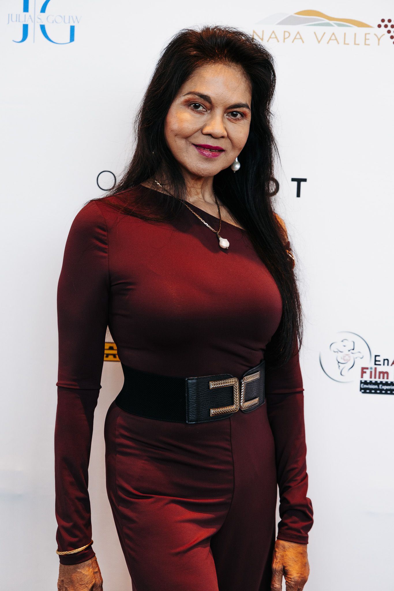 Person wearing a burgundy long-sleeve dress at a formal event.