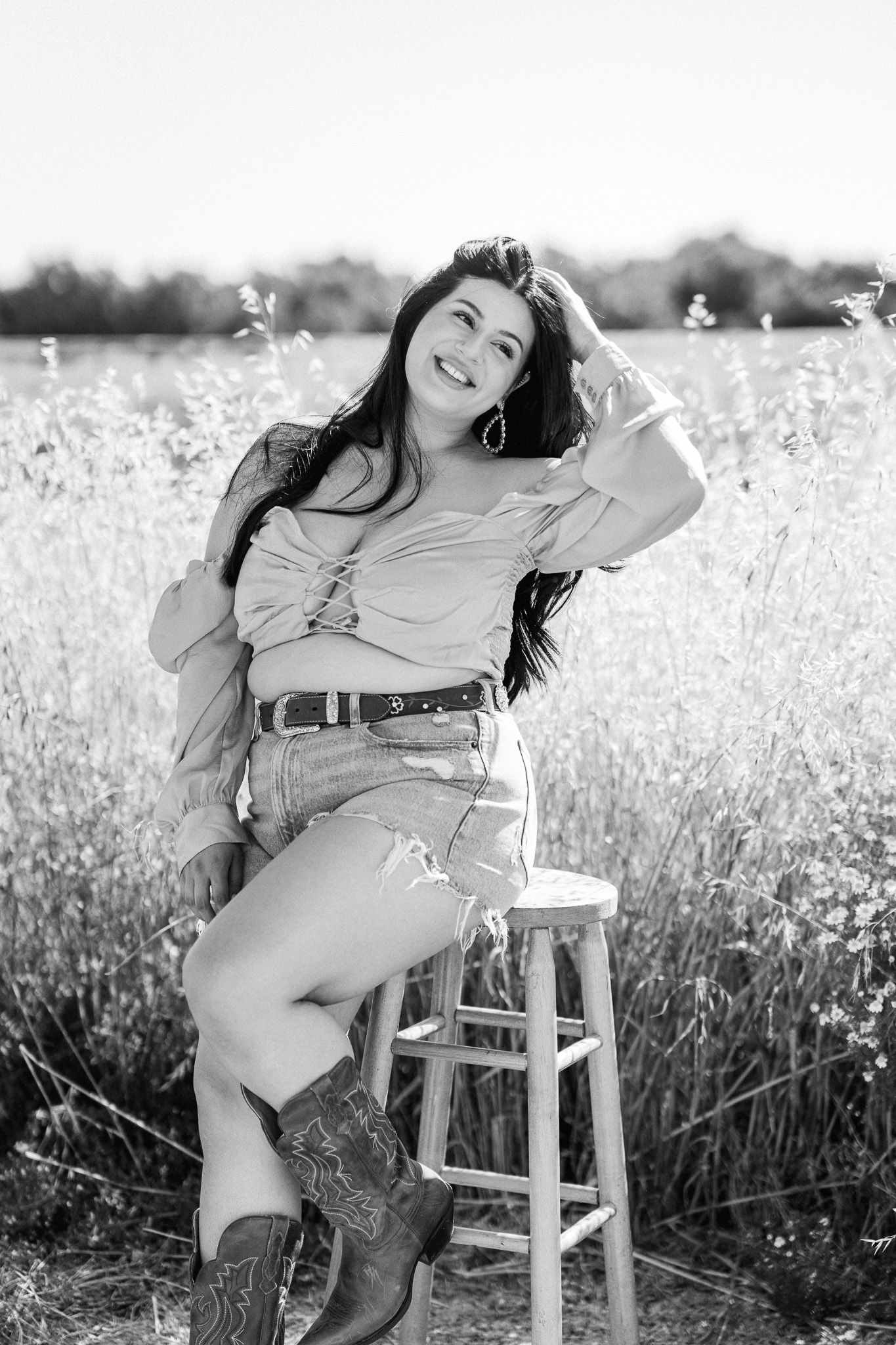 Black and white photo series of someone posing on a wooden stool in a wildflower field wearing cowboy boots.