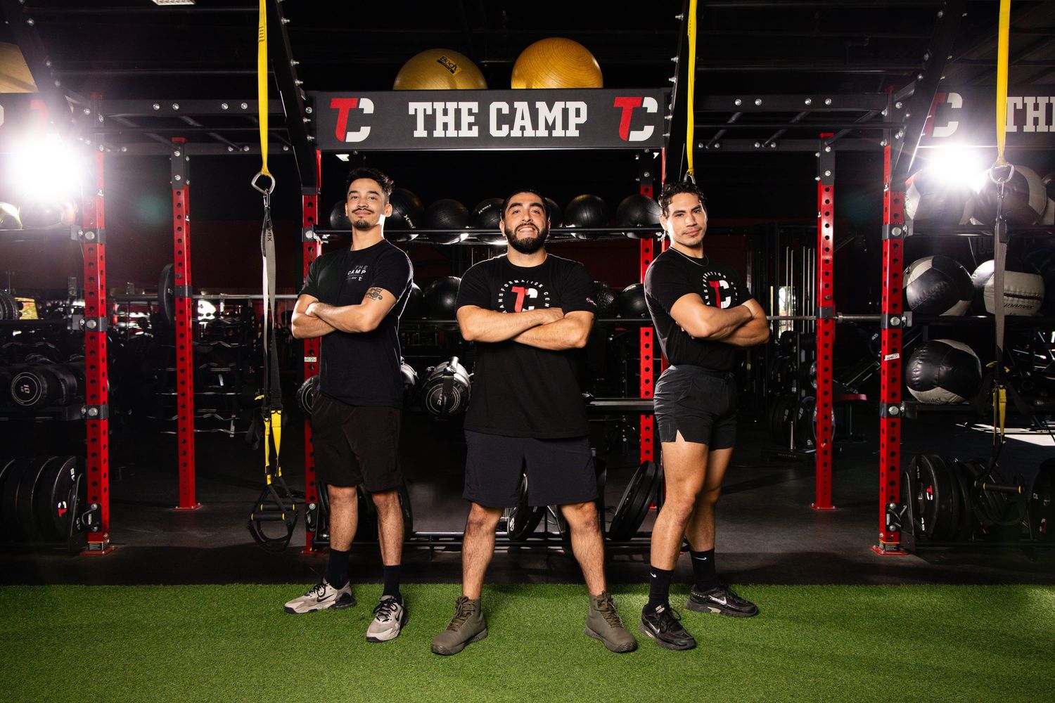 A group of athletes training in a dark gym with red lighting and exercise equipment.
