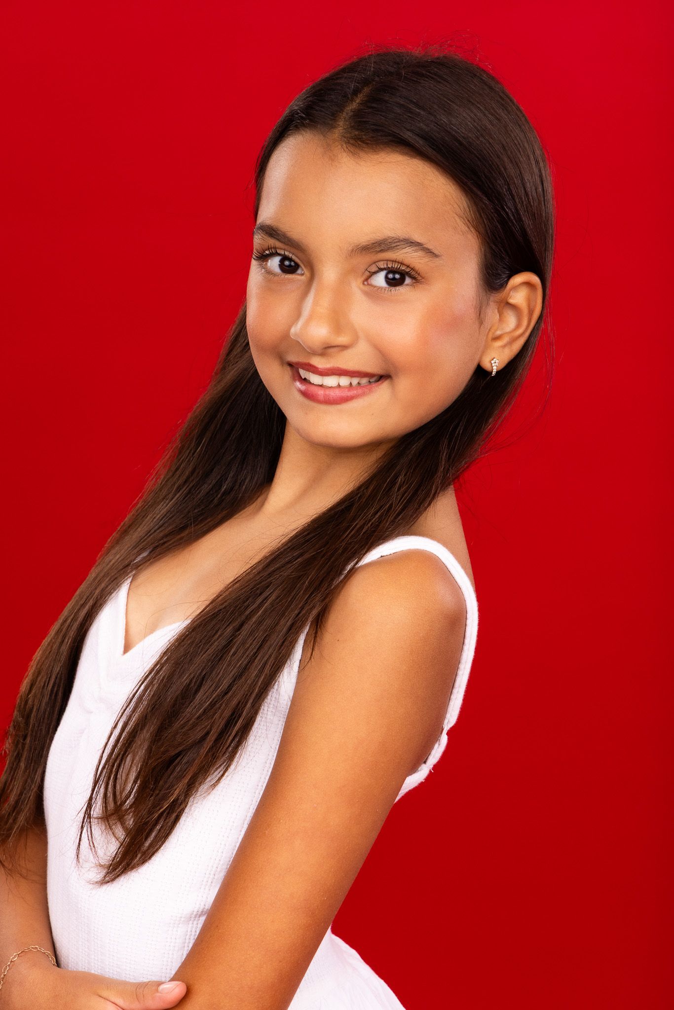 Portrait series of young girl in white top against vibrant red background showing different cheerful expressions.