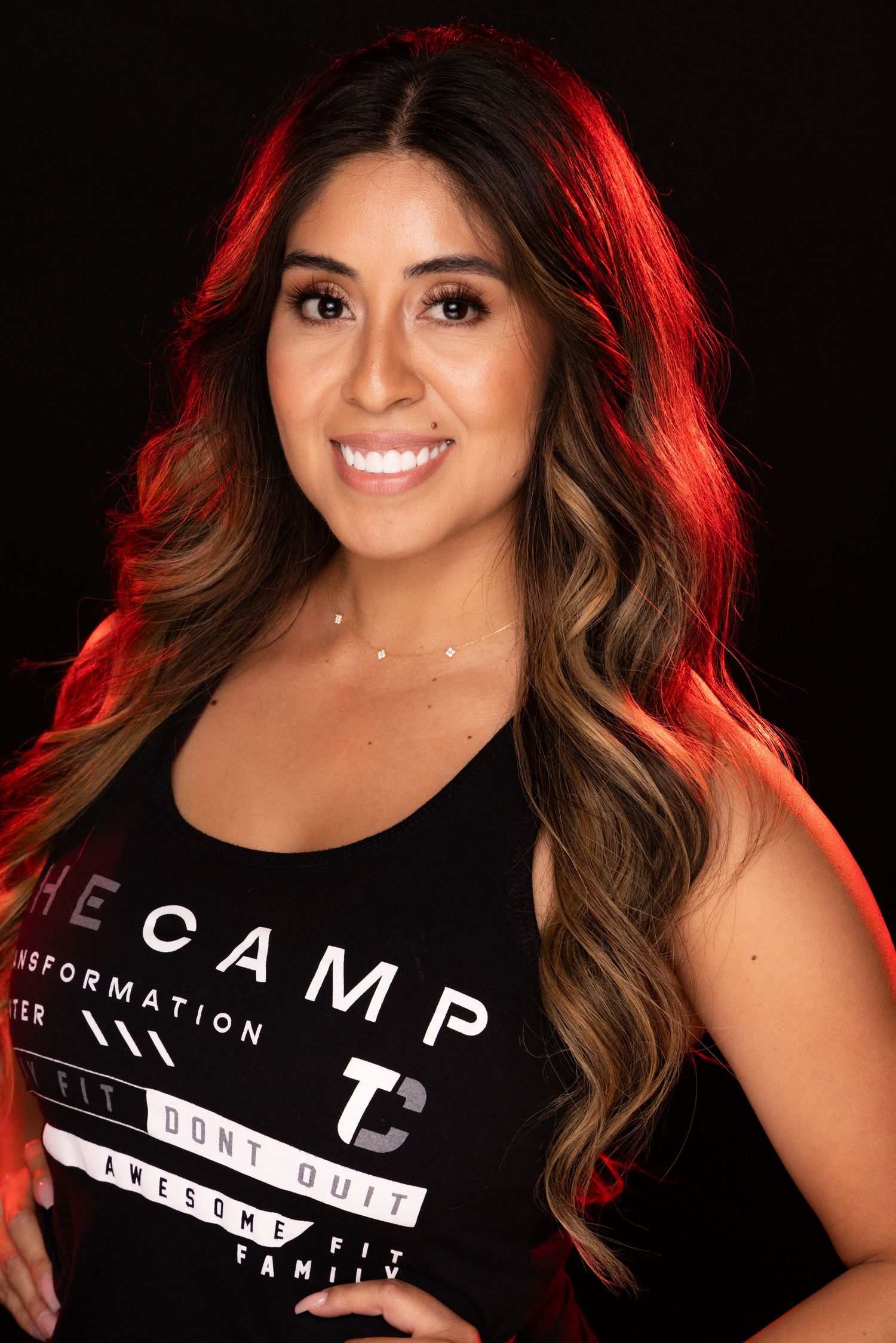 Portrait of a woman in a black t-shirt with text against dark background with dramatic red lighting.