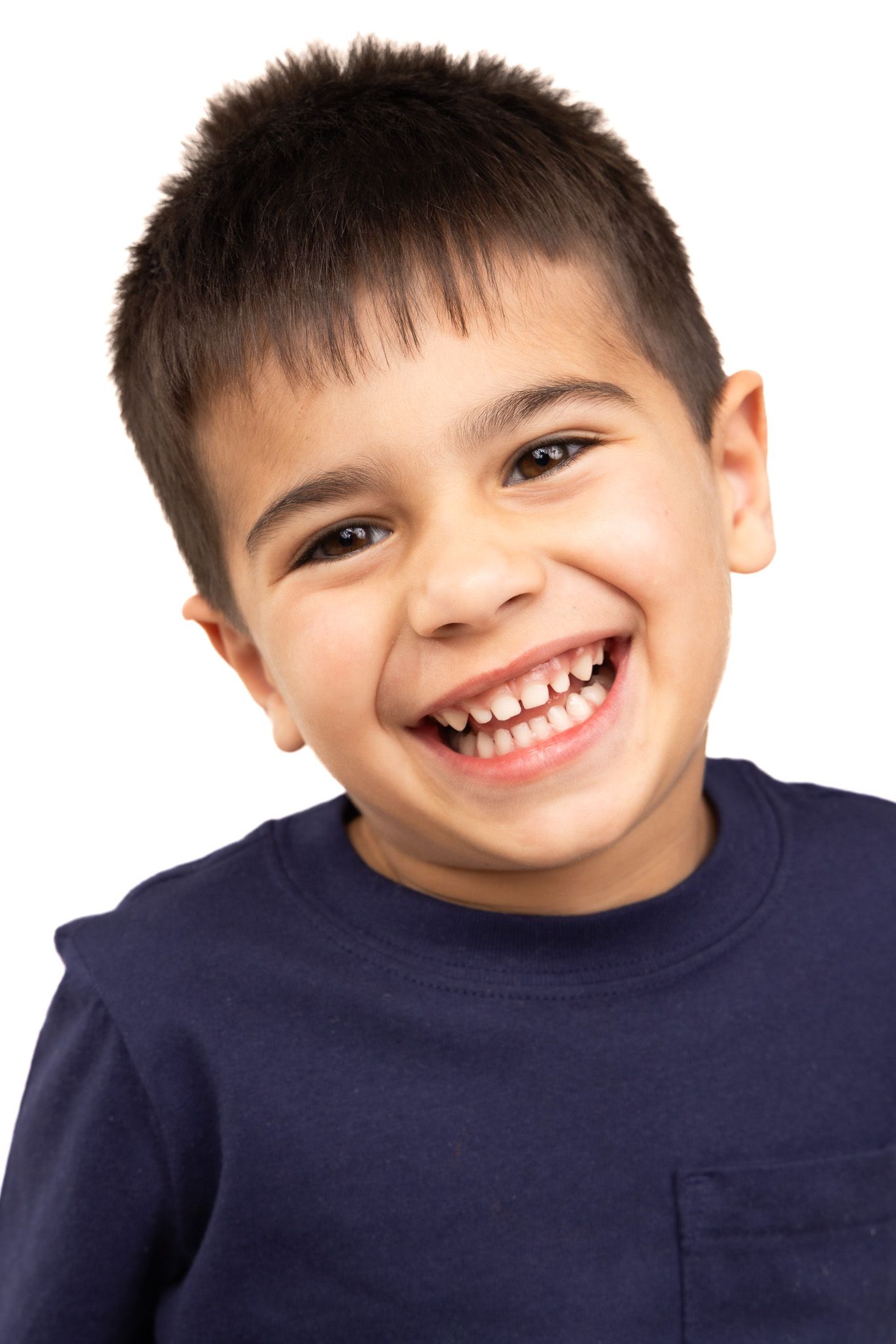 Child in navy blue shirt showing bright smile against white background.