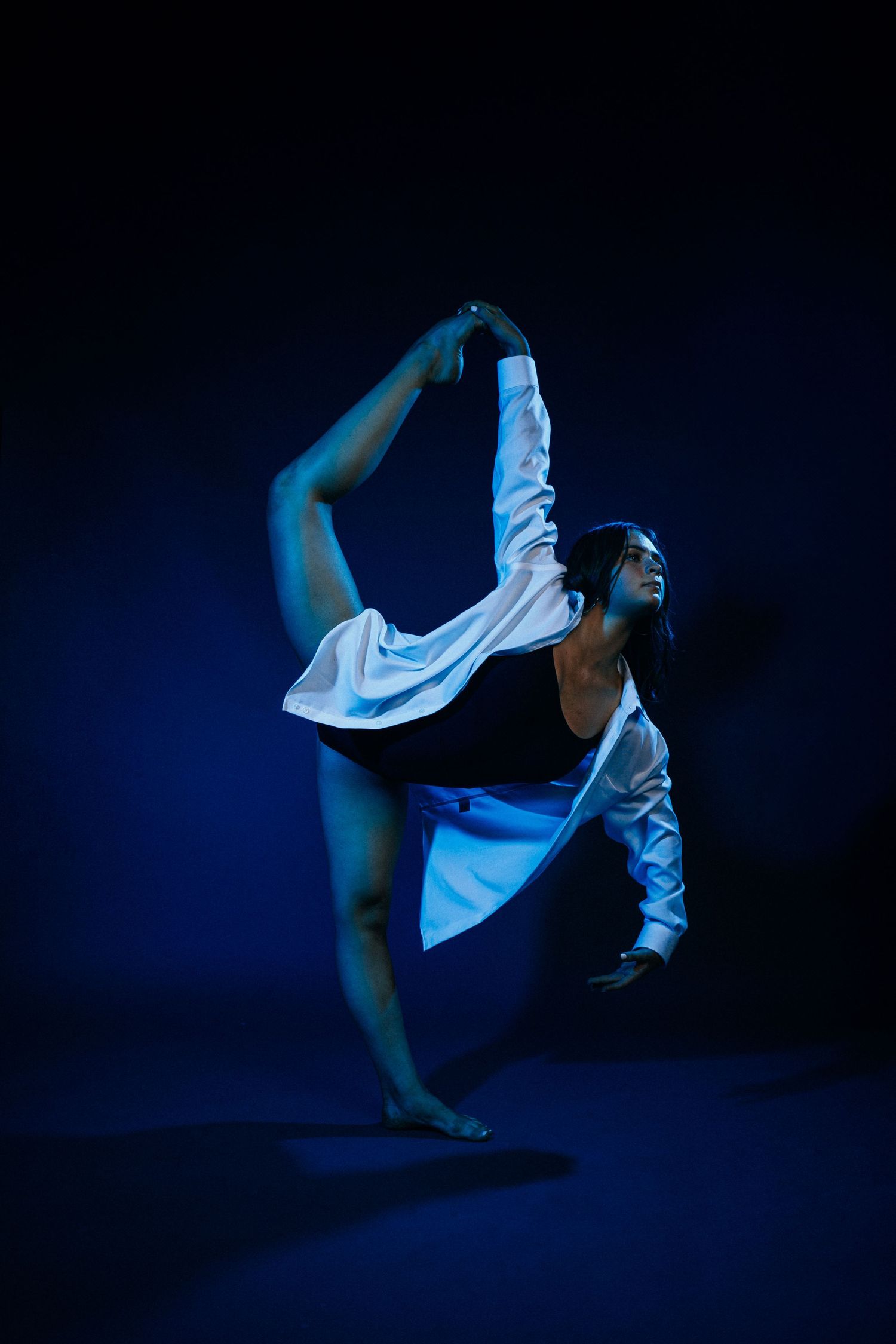 Modern dance sequence photographed in low-key lighting showing athletic movements in white costume.