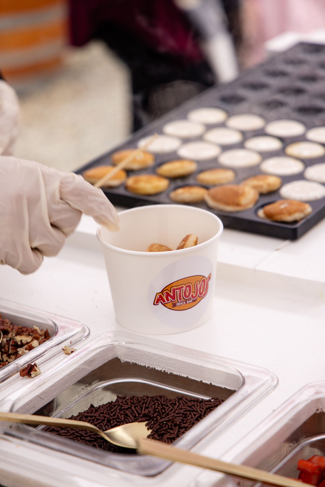 Food preparation station with multiple trays showing pancakes and toppings being assembled.