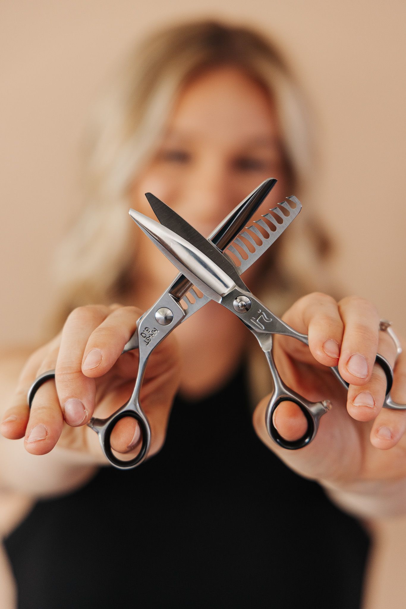 A sequence of hands holding and positioning scissors in different angles against a beige background.