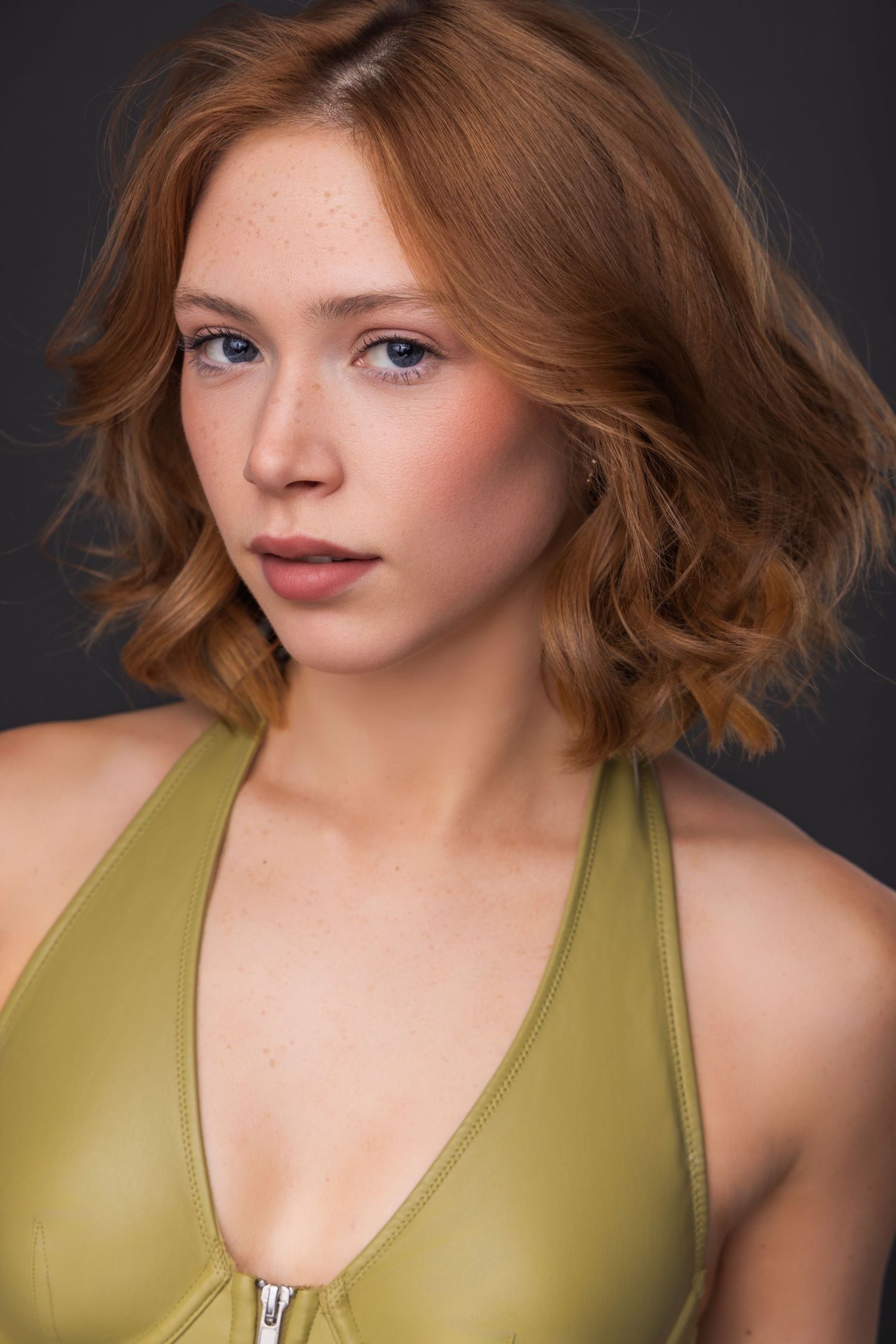 Portrait series showing different angles and expressions while wearing an olive green tank top against a dark background.