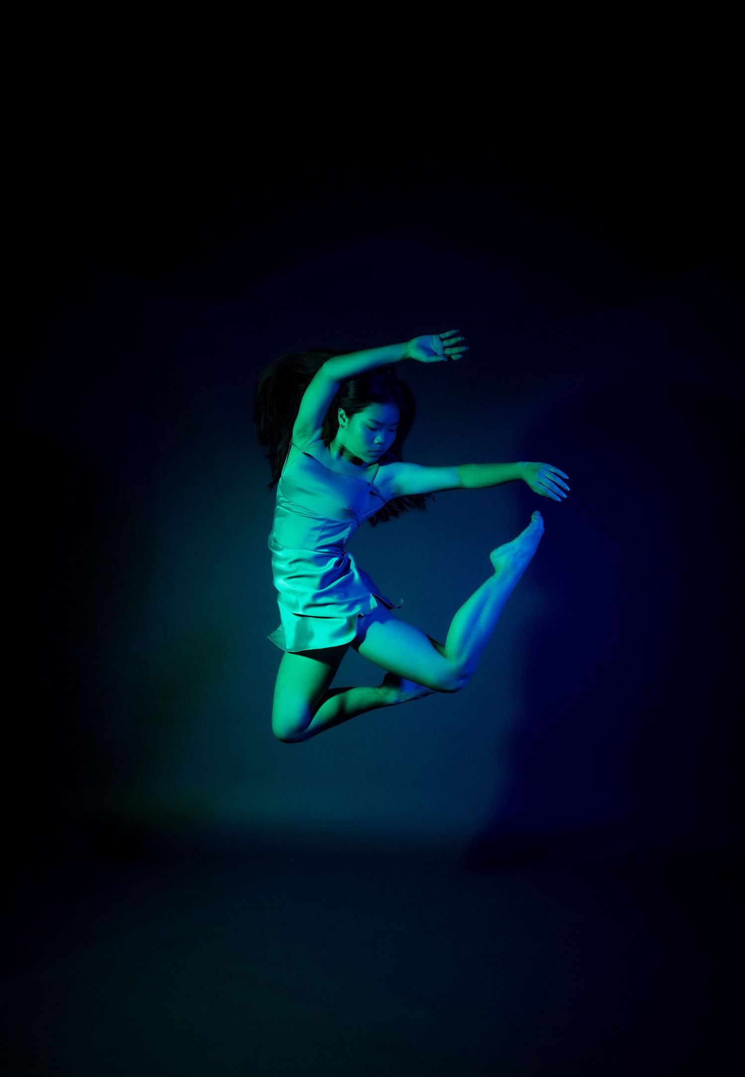Athletic dance movements photographed in ethereal teal and blue lighting.