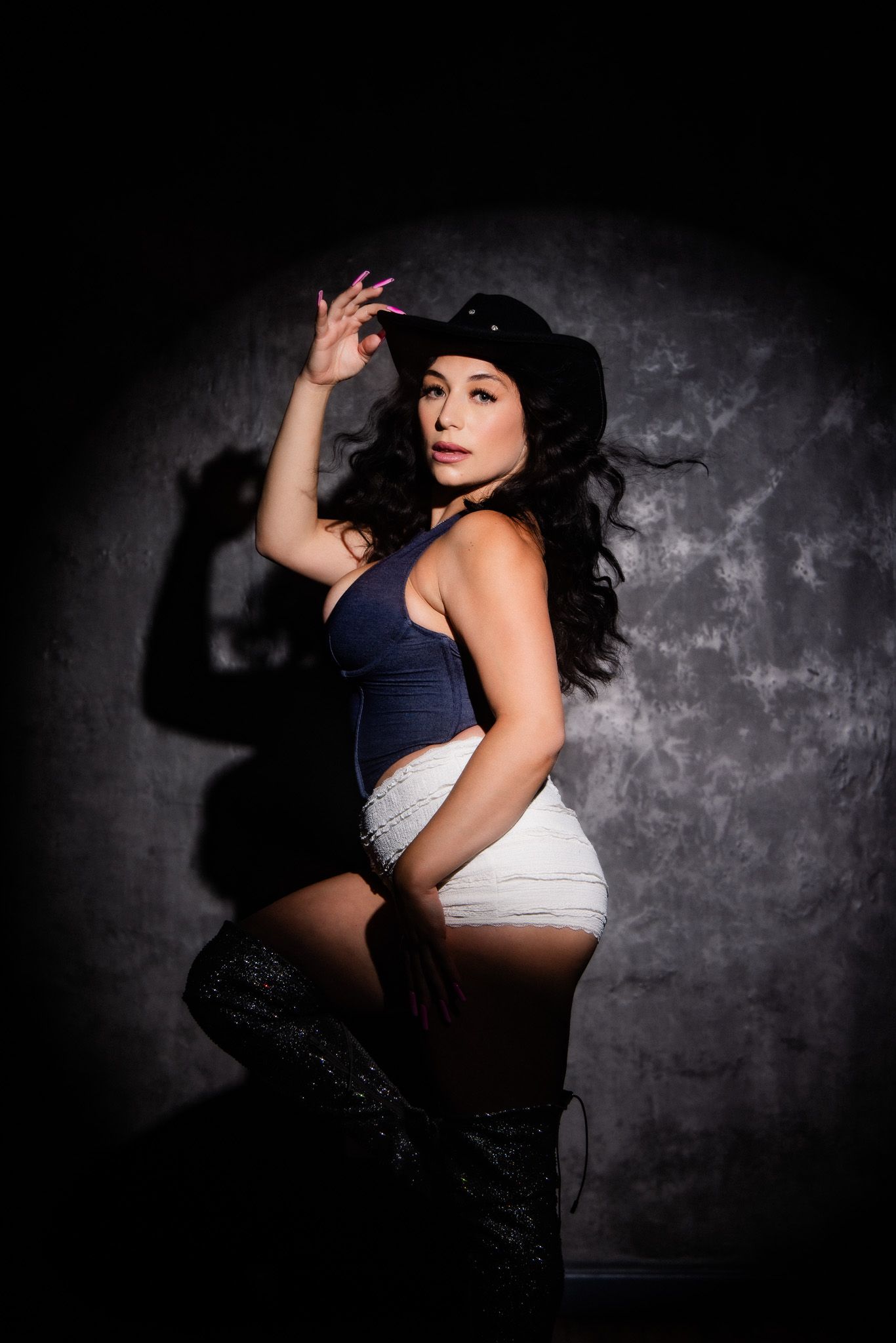 Artistic studio portraits in moody lighting featuring dark textured backdrop and contrasting shadows.
