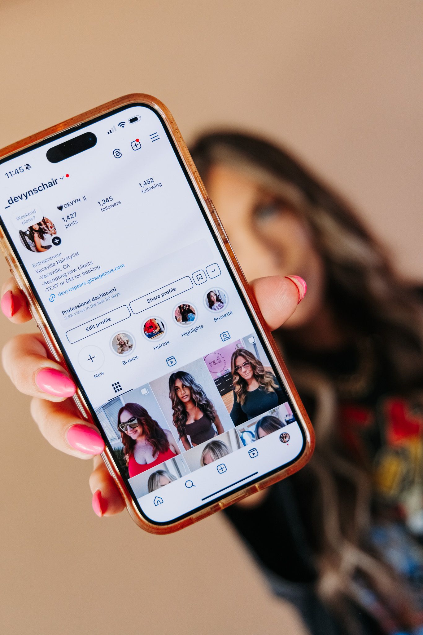 Hand holding smartphone displays social media profile interface against blurred background.