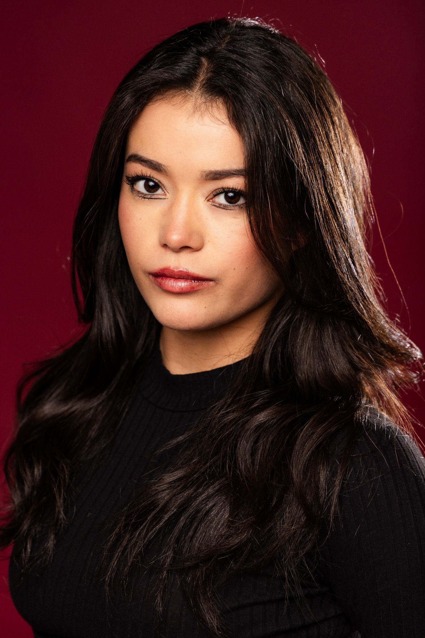 Studio portrait series showing dark hair movement against deep burgundy background with dramatic lighting.