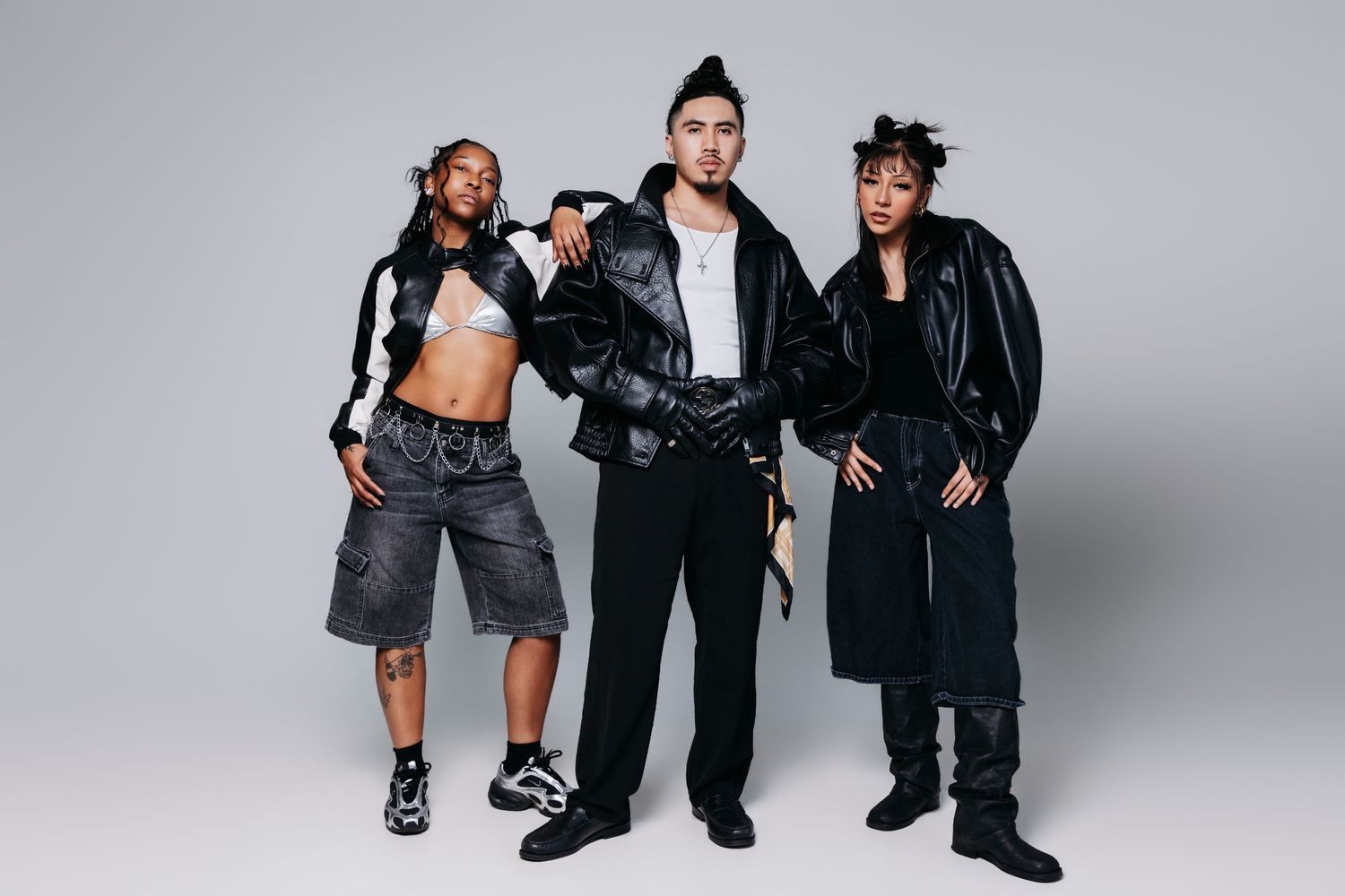 Group of people in casual streetwear outfits posing together against a light gray studio background.