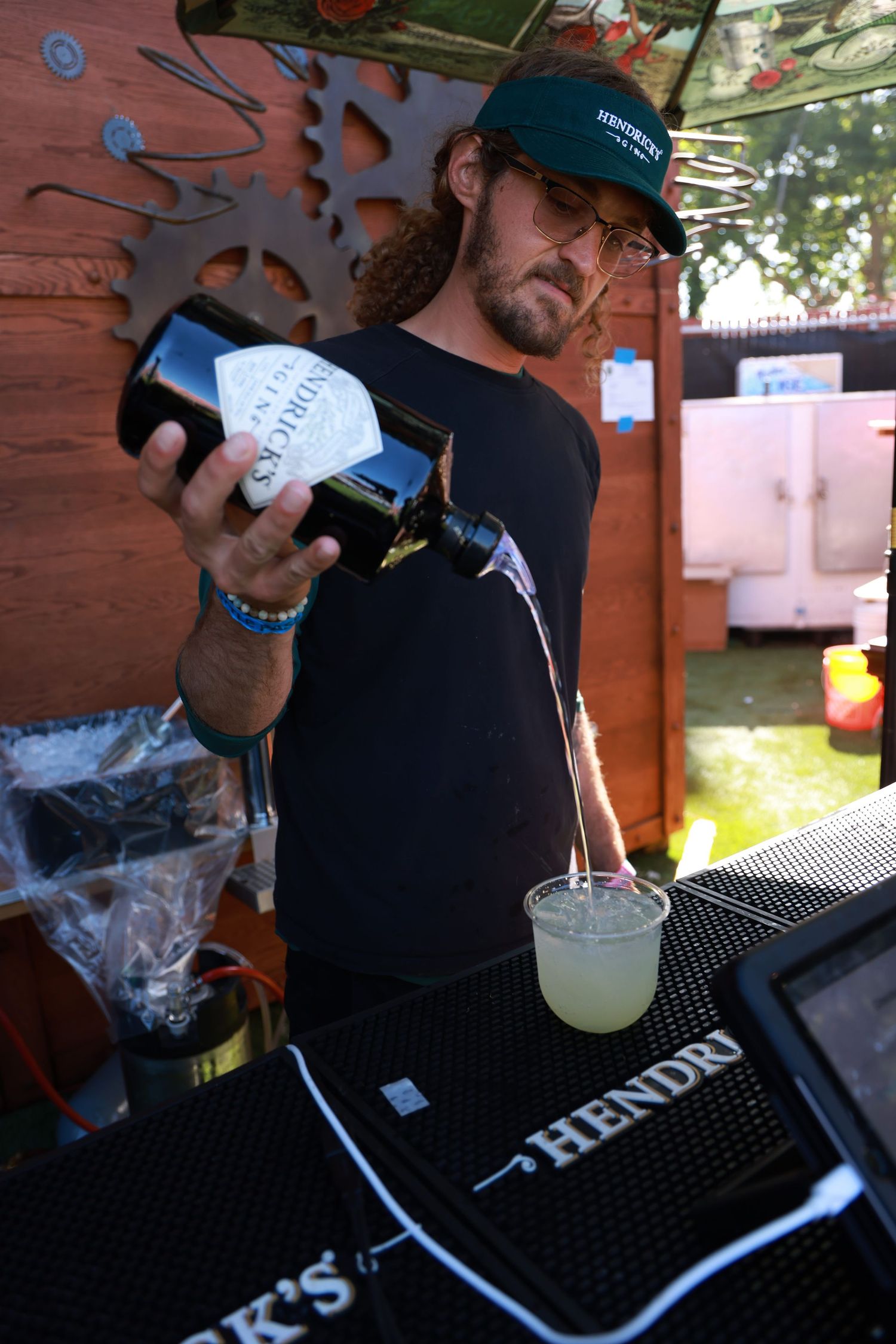 Bartender working behind black bar mat with Hendricks gin branding.