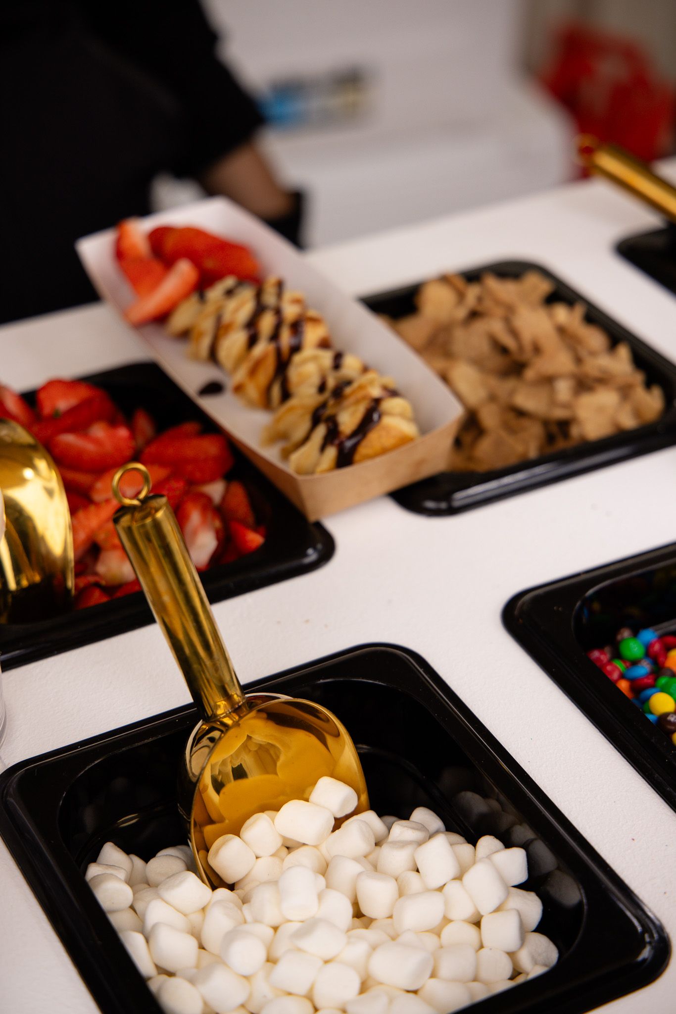 Assorted snacks and candies arranged in black serving trays for an event or party setup.