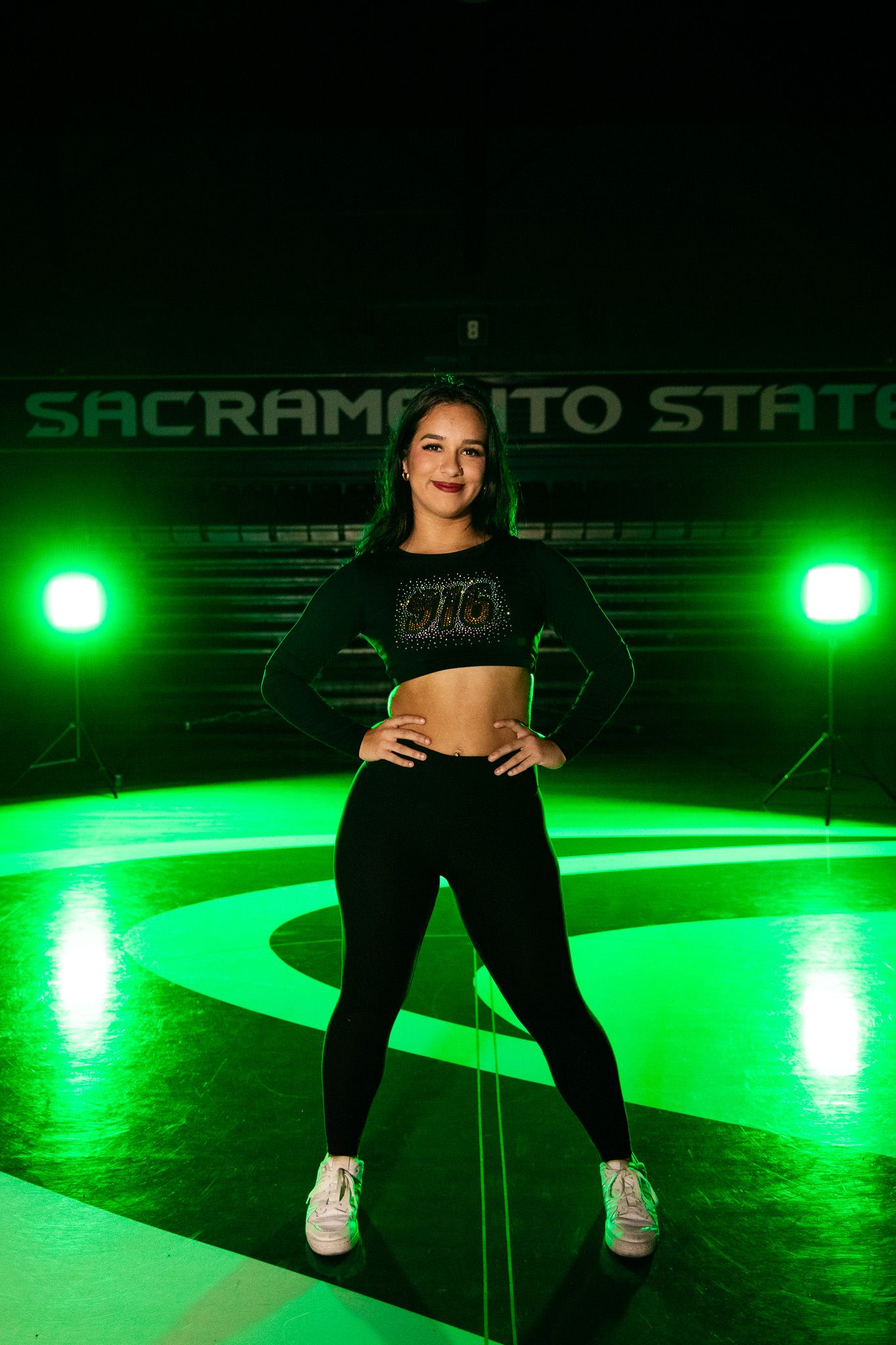 A dance performance on stage illuminated by bright green lighting at Sacramento State venue.