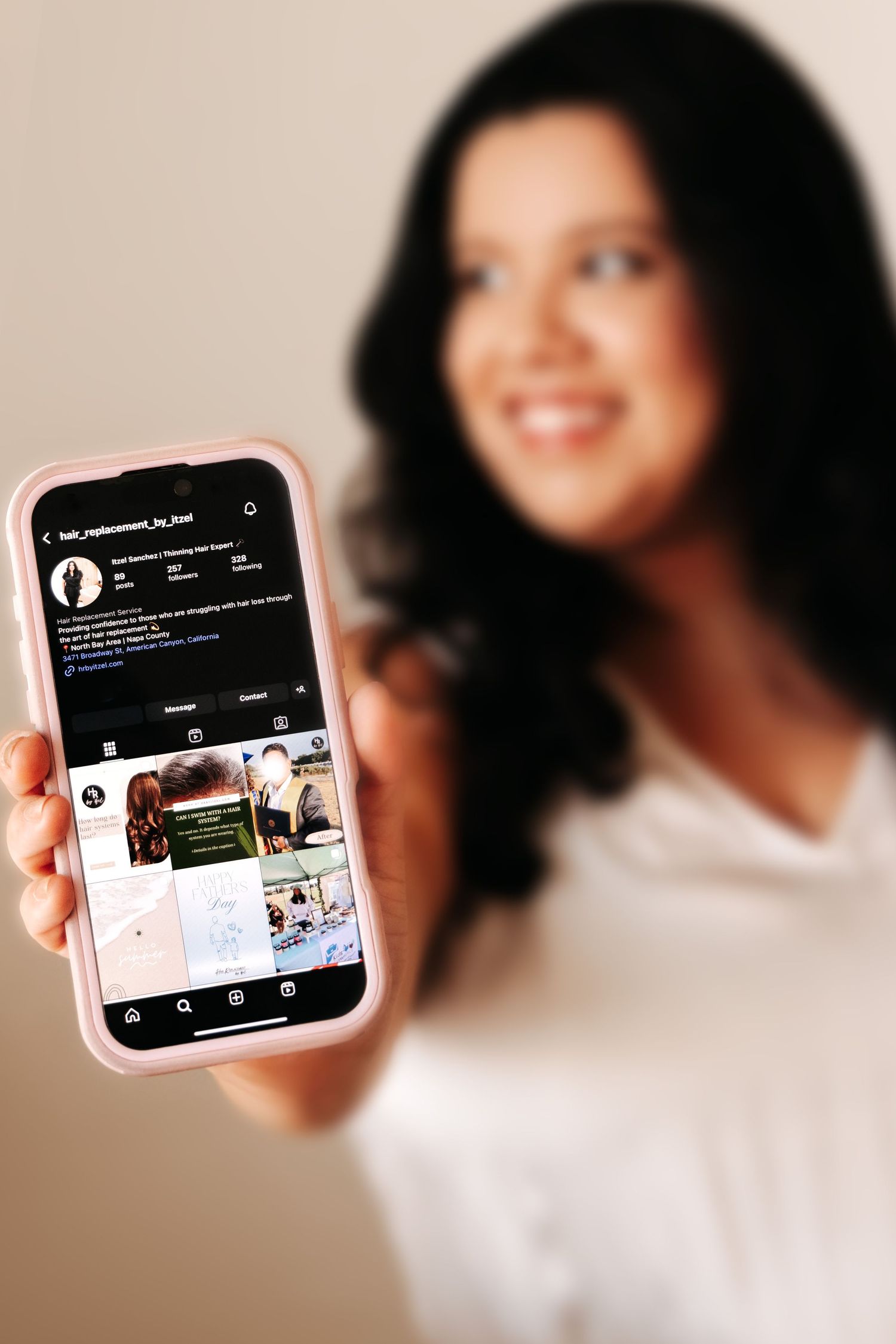 Hand holding a pink phone case displaying social media content against a soft blurred background.