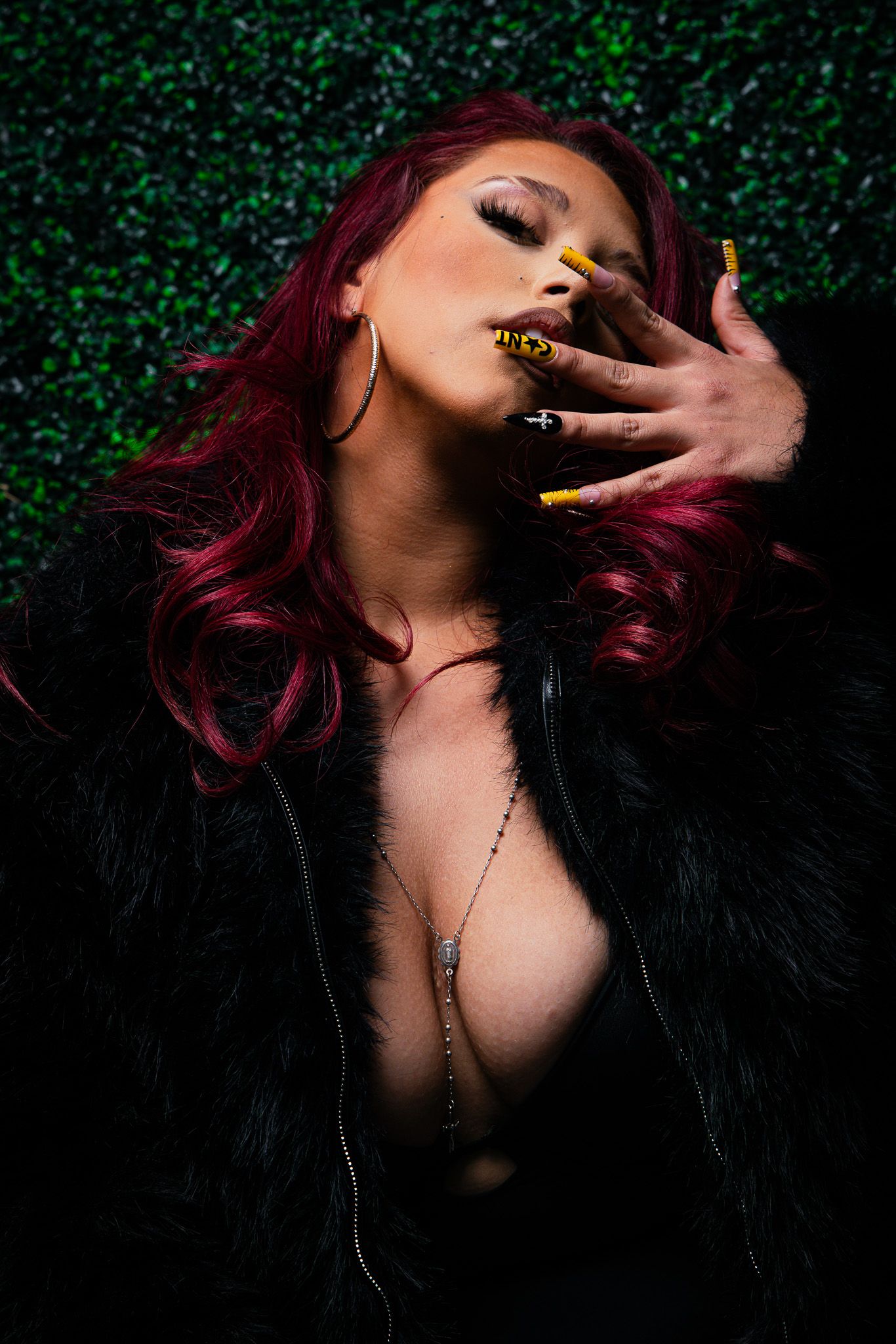 Artistic portrait series showing dramatic poses against dark foliage with burgundy hair and moody lighting.