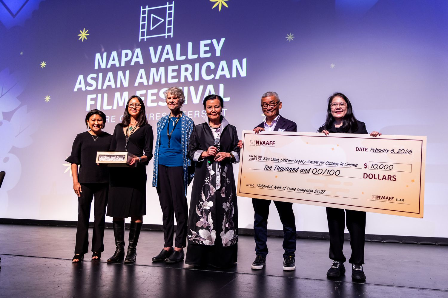 Group of people on stage at the Napa Valley Asian American Film Festival accepting an award check.
