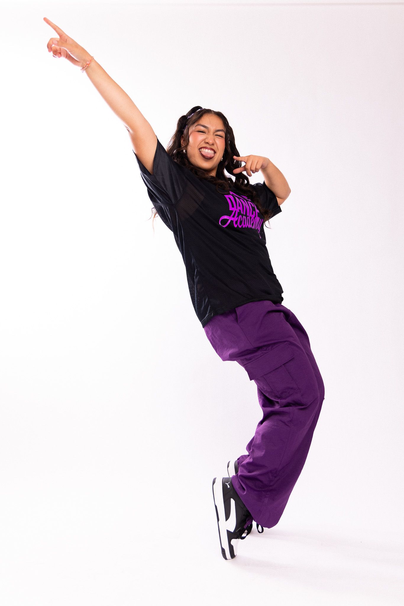 Dancer in black t-shirt and purple pants performs energetic jumping poses against white background.