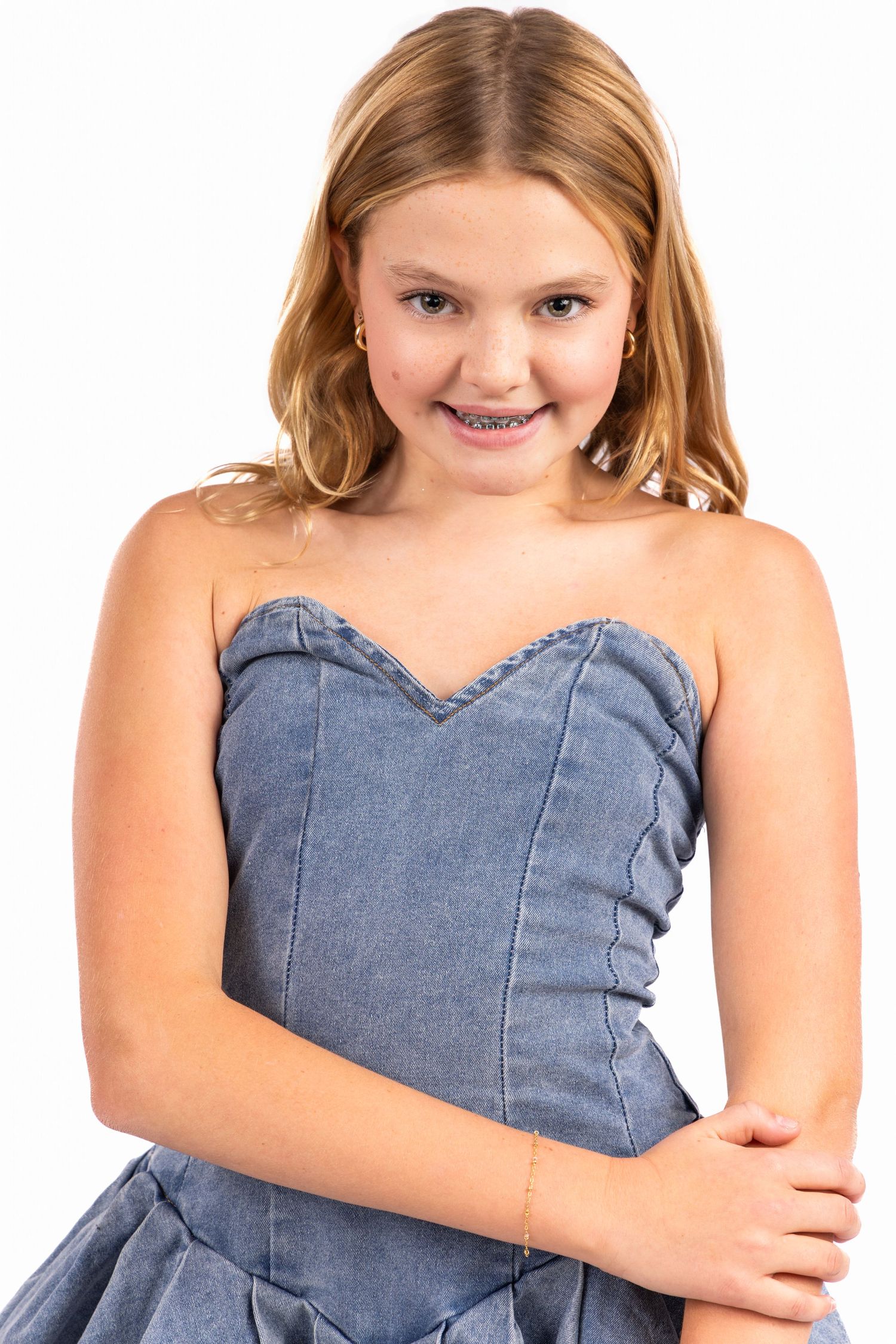 Young person wearing a blue denim dress poses playfully in a sequence of connected photos.