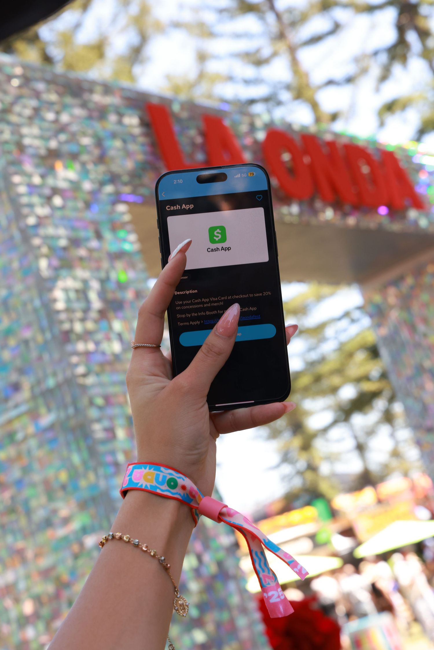 Hand holding a mobile phone displaying a dark interface screen against a colorful blurred background.