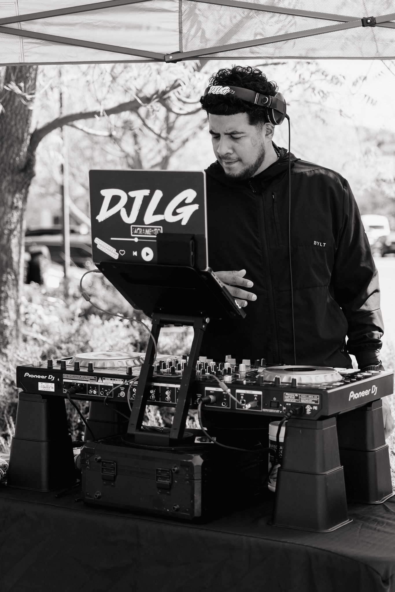 DJ setup with turntables and equipment under a white canopy tent at an outdoor event.