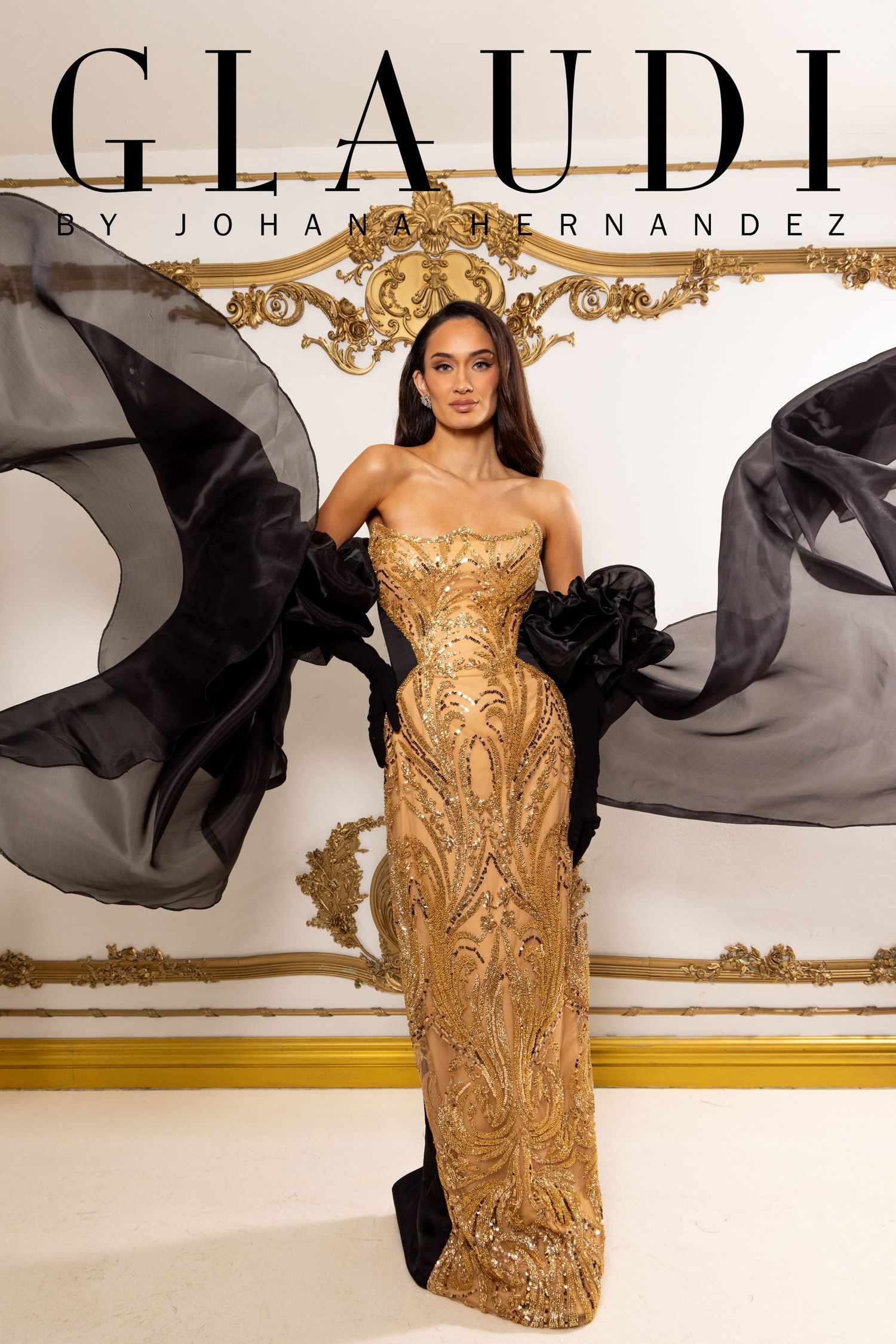 Model wearing a gold sequined strapless gown by Glaudi by Johana Hernandez with flowing black chiffon sleeves.