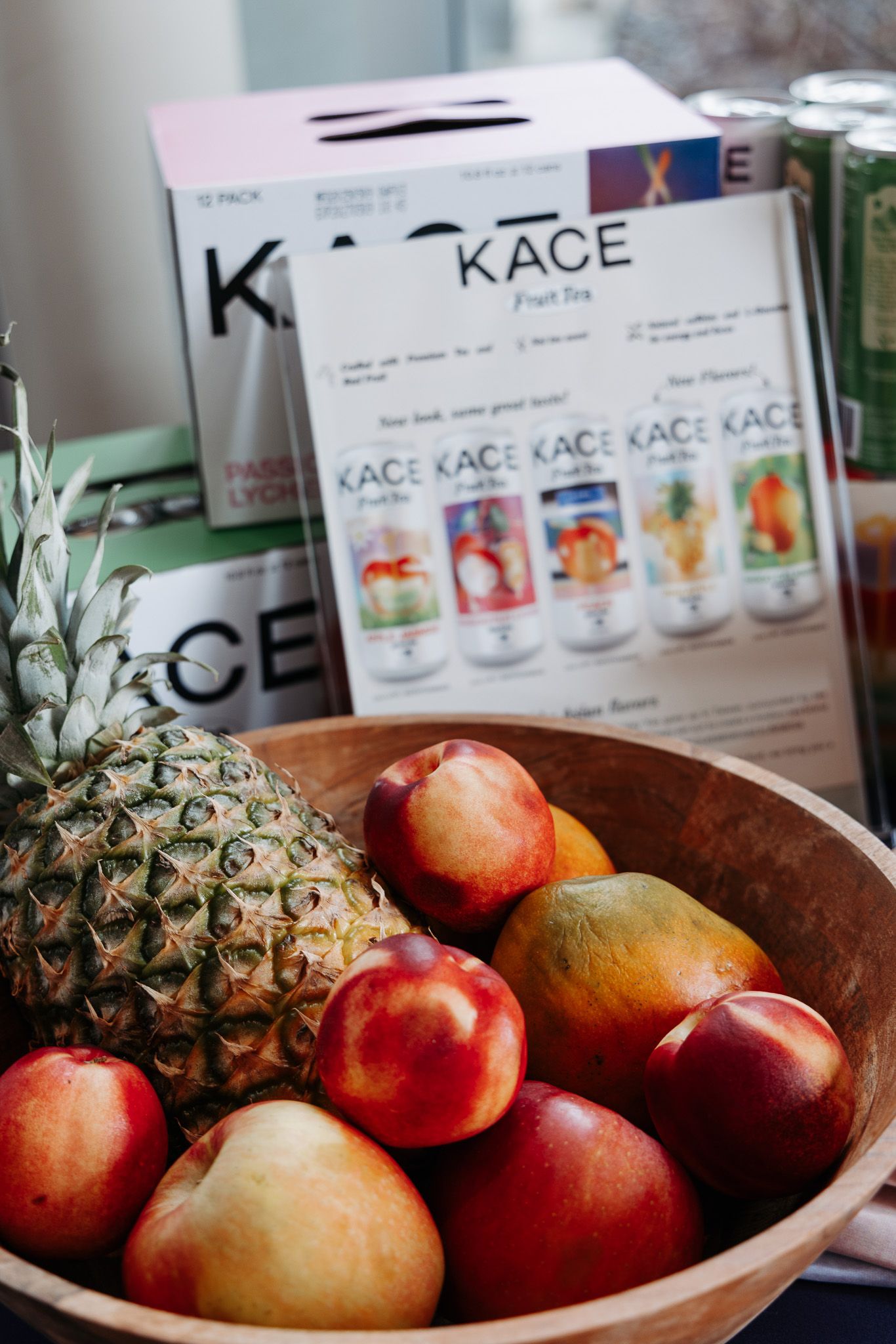 Fresh fruit bowl with pineapple and apples next to Kace beverage products.