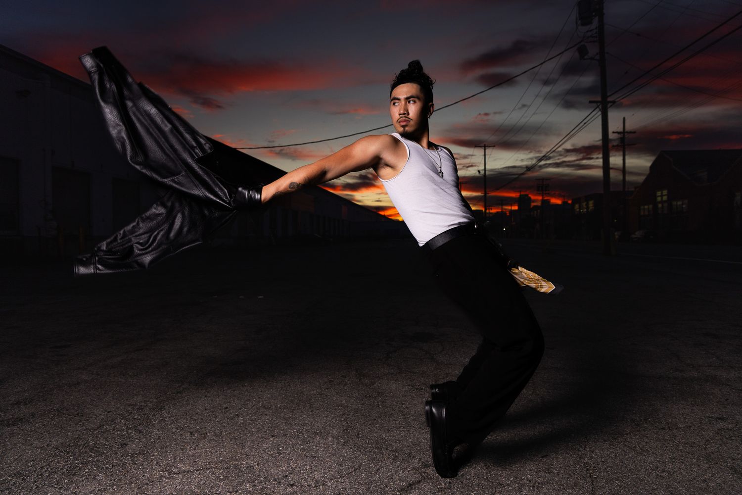 A silhouetted figure performs a dynamic breakdancing move against a dramatic sunset sky.