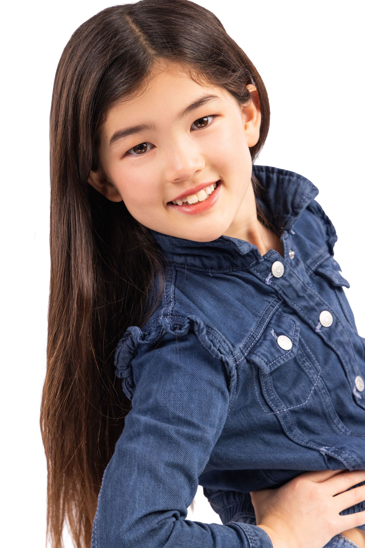 Young model wearing blue denim jacket poses with bright smile against white background.