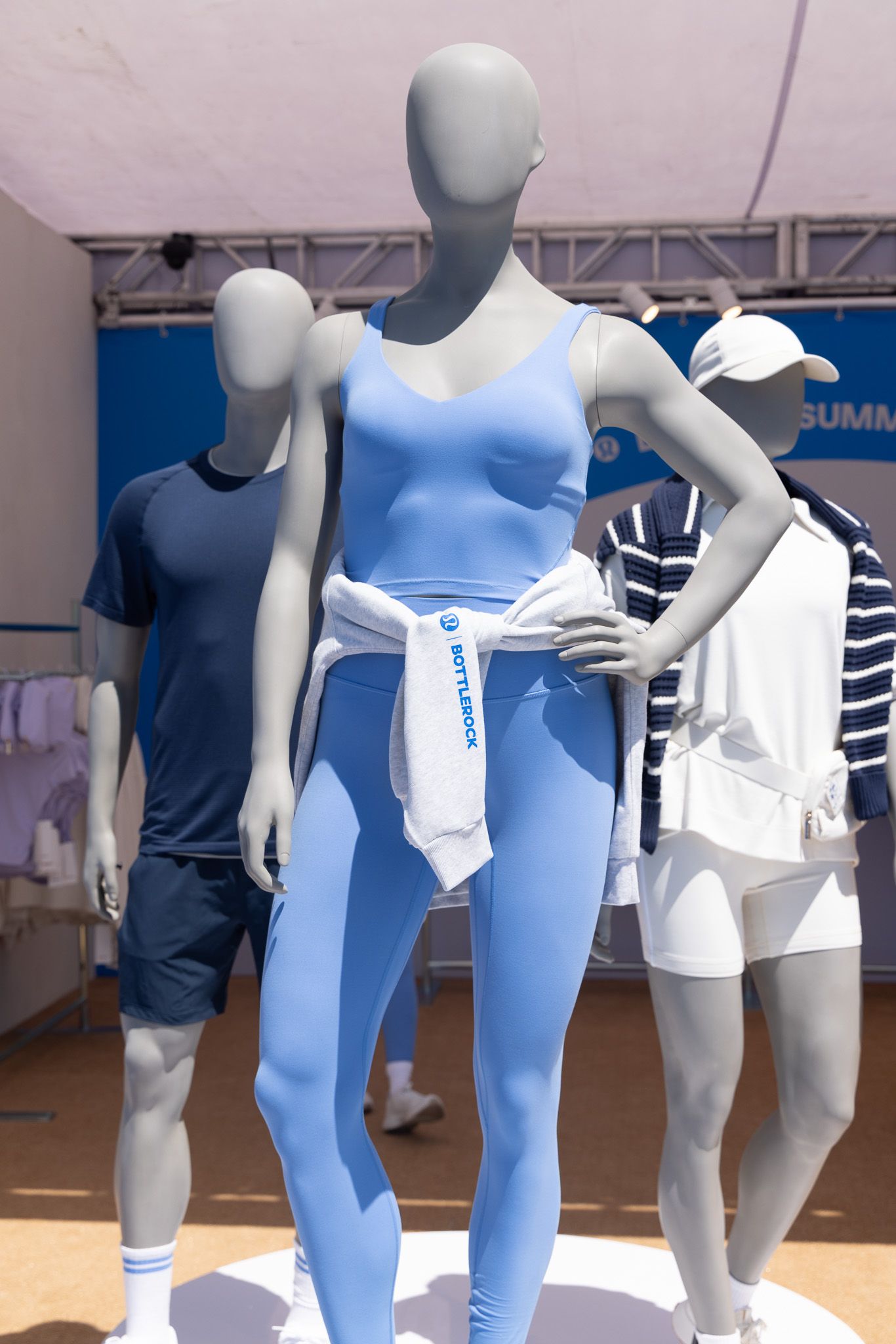 Store mannequins display blue and white athletic wear in a retail setting, showing various sportswear combinations.
