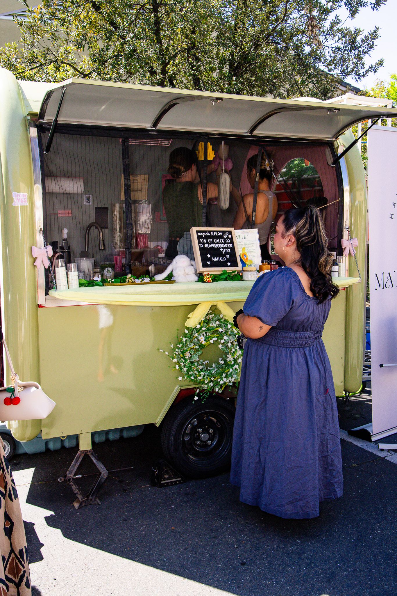 A mobile food service trailer with yellow exterior serving customers at an outdoor event.