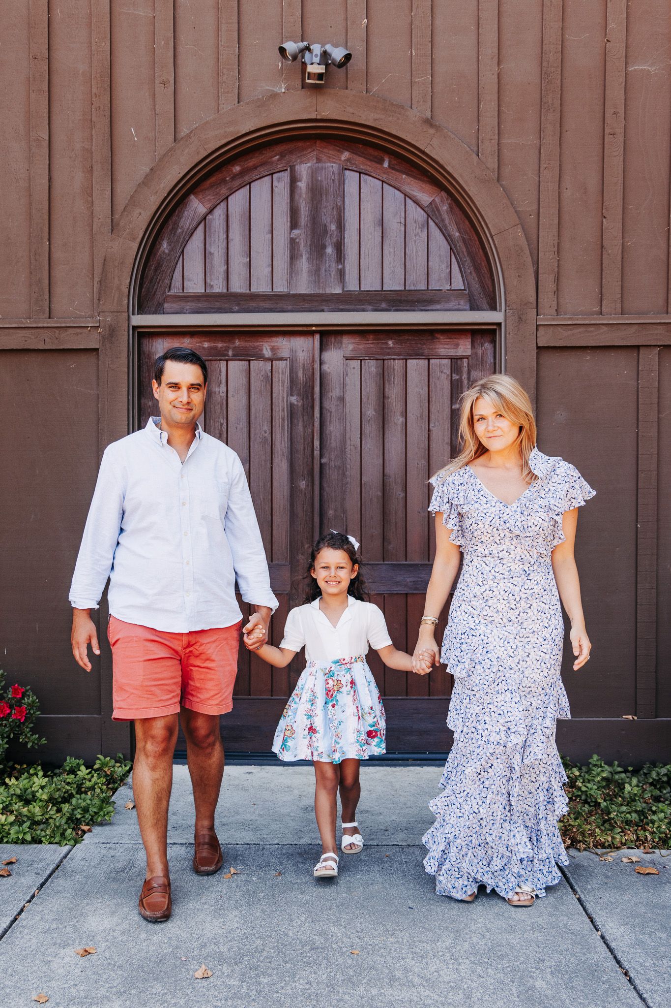 A series of five similar photos showing a family posing in front of a wooden barn door wearing coordinated outfits.