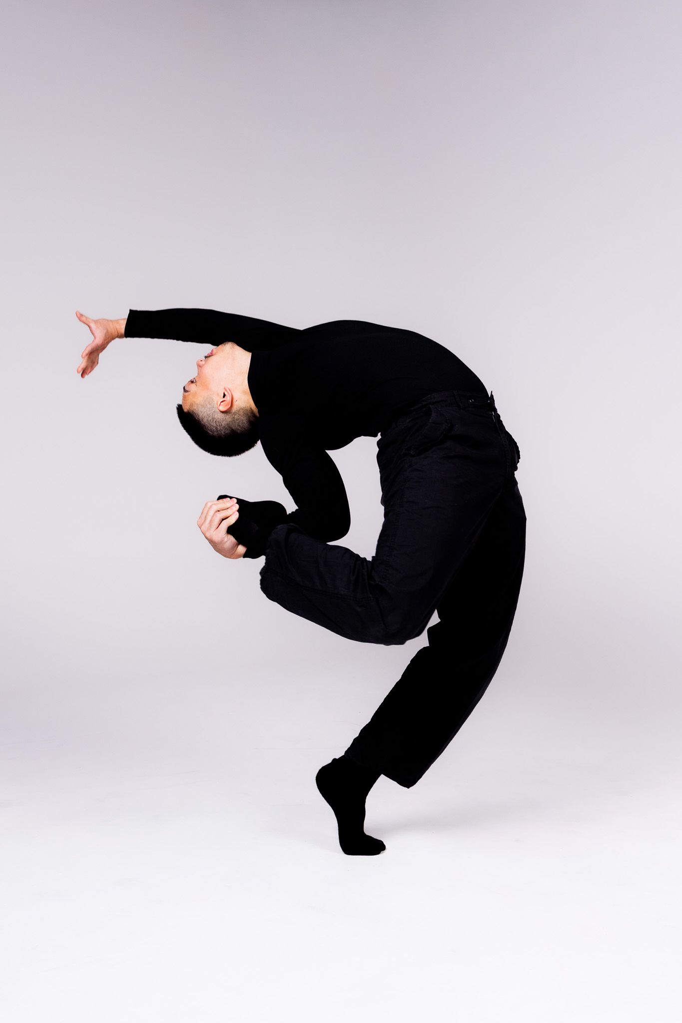 Sequence showing person in black outfit performing graceful flowing backbend movement against light gray background.