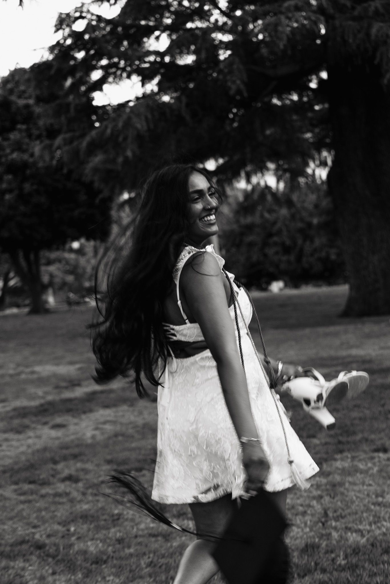 A woman in a white dress dances and spins gracefully across a grassy field in a black and white photograph series.