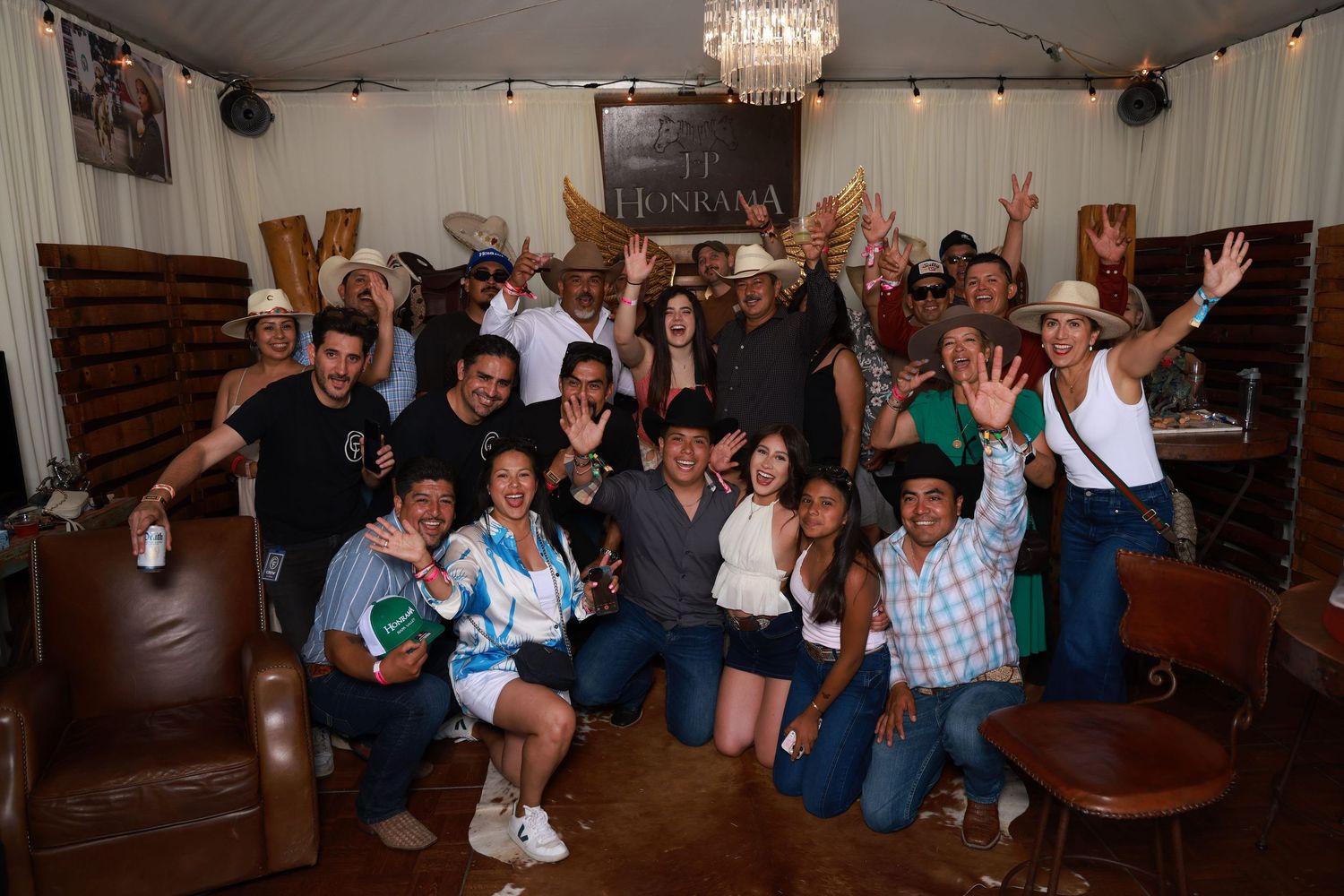 Large group of friends posing together inside a rustic venue, smiling and celebrating at what appears to be a party.