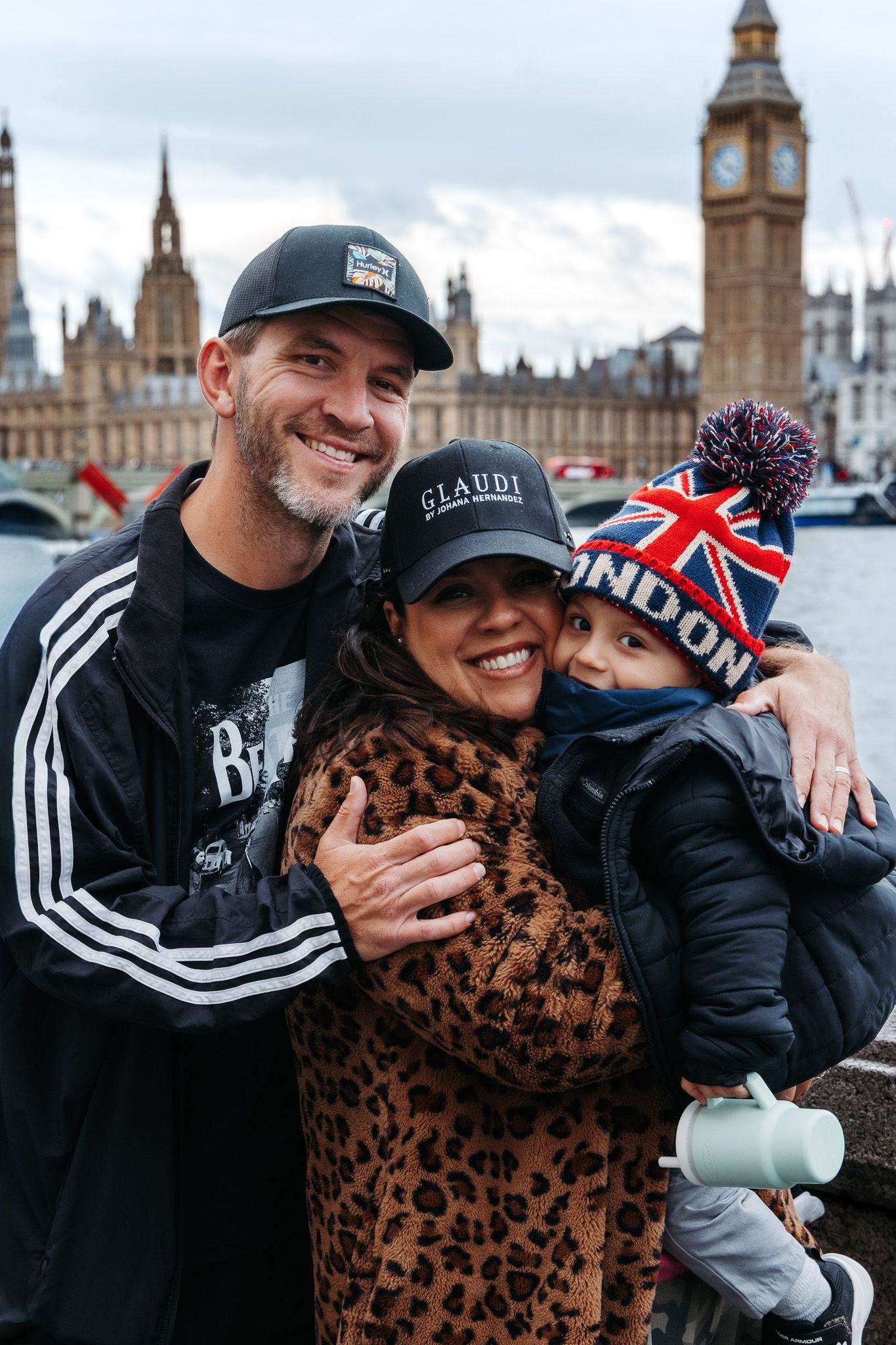 Two people laughing and embracing while sightseeing near Big Ben and the Houses of Parliament in London.