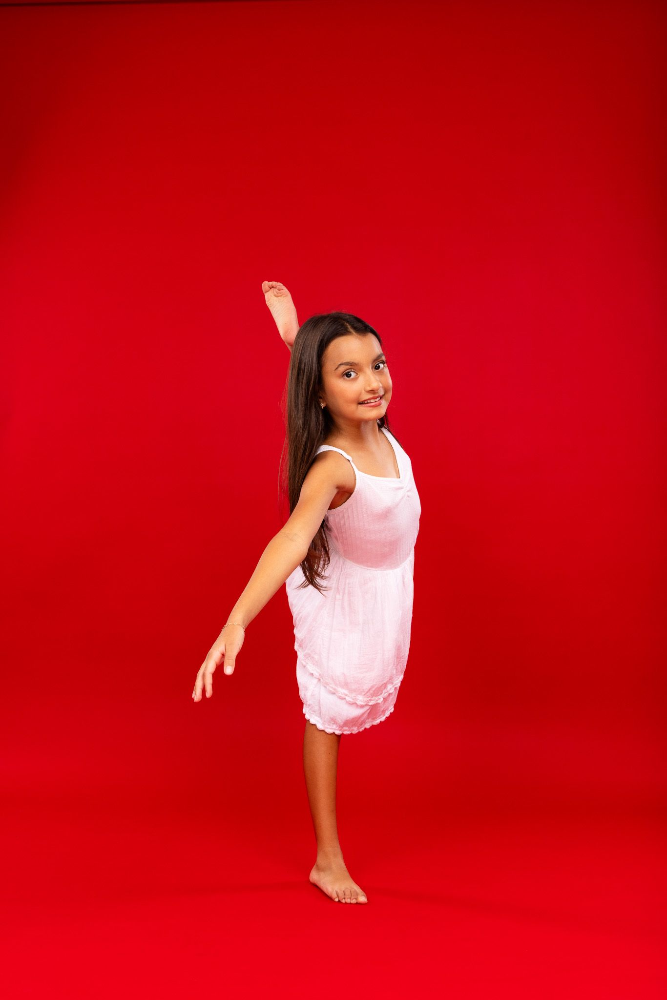 Dancer in pink leotard strikes dynamic poses during performance against red background.